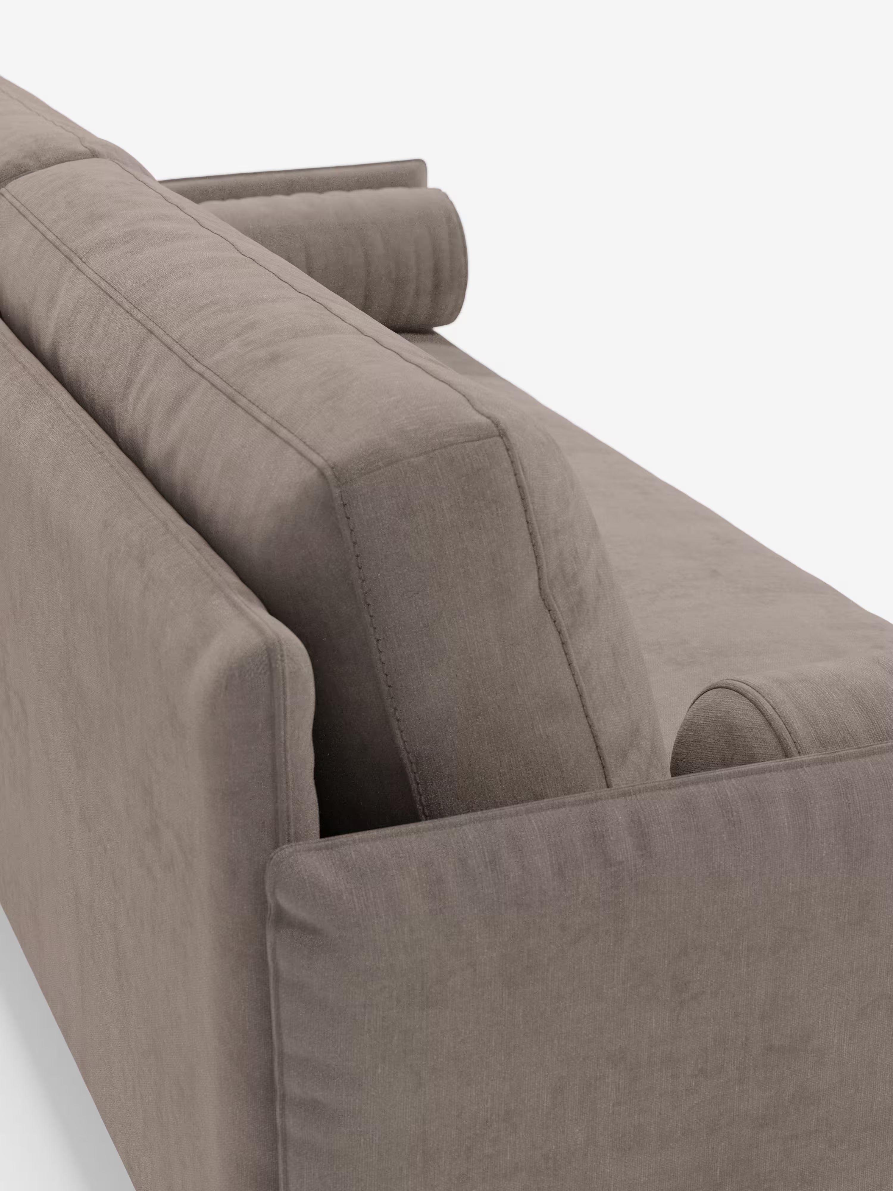 Primo piano del divano lineare a 2 posti “Basalto” di Divani.Store, rivestito in tessuto T31 color taupe smacchiabile. L'immagine mette in risalto lo schienale e un bracciolo, con due cuscini cilindrici appoggiati alle due estremità. Il divano si caratterizza per le linee pulite, i morbidi cuscini e una texture liscia e opaca che incarna il vero design minimalista. Il divano poggia su un'elegante base in metallo su uno sfondo bianco uniforme.