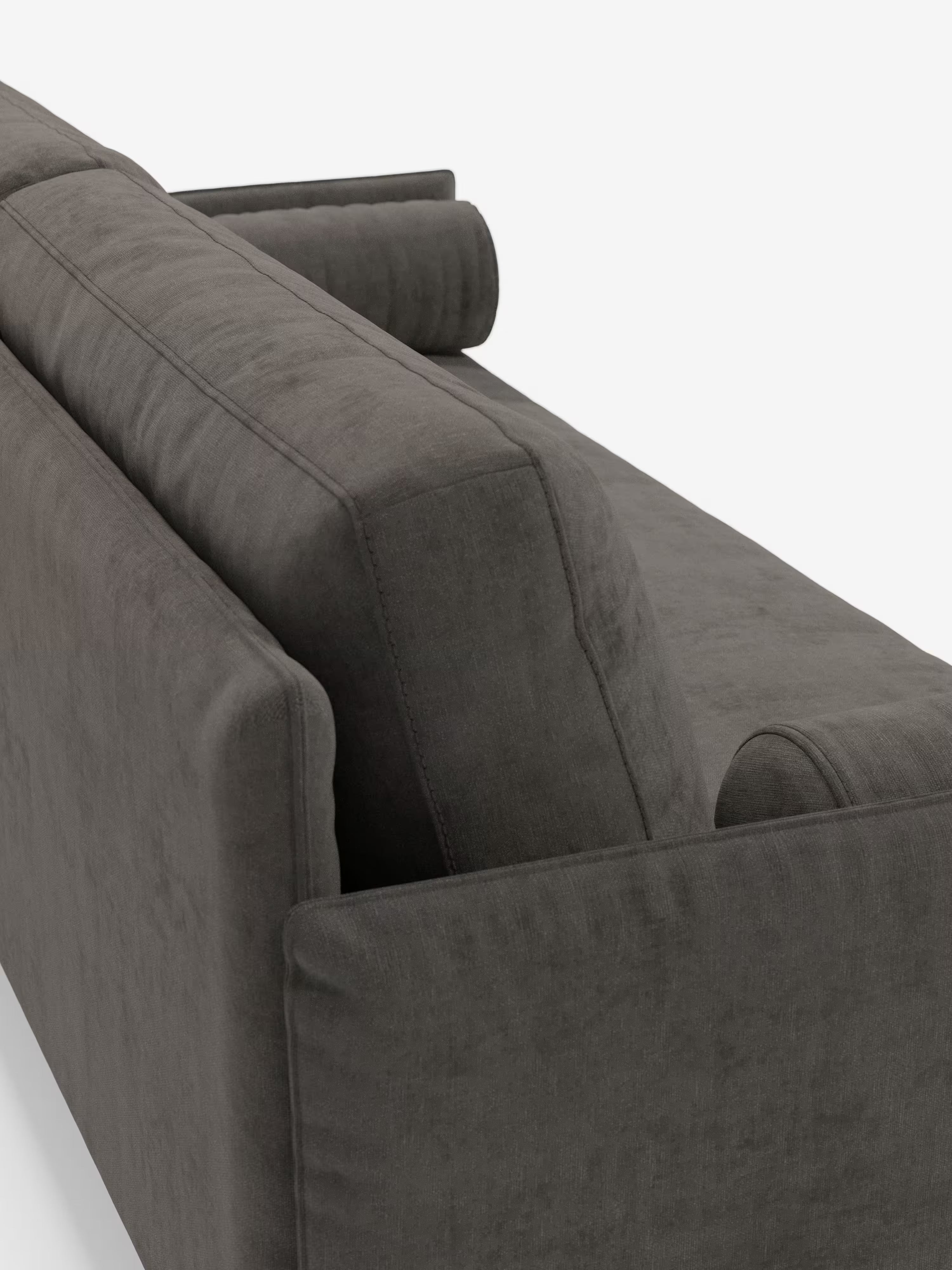Primo piano del divano lineare Basalto a 2 o 3 posti con seduta unica e base in metallo, rivestito in tessuto smacchiabile T31 di Divani.Store, caratterizzato da un rivestimento in tessuto moderno grigio scuro e da un design minimalista. Il divano è ripreso da dietro, mettendo in risalto i cuscini superiori e quelli dello schienale, insieme a un cuscino cilindrico abbinato posizionato sul bracciolo destro. Lo sfondo è bianco a tinta unita.