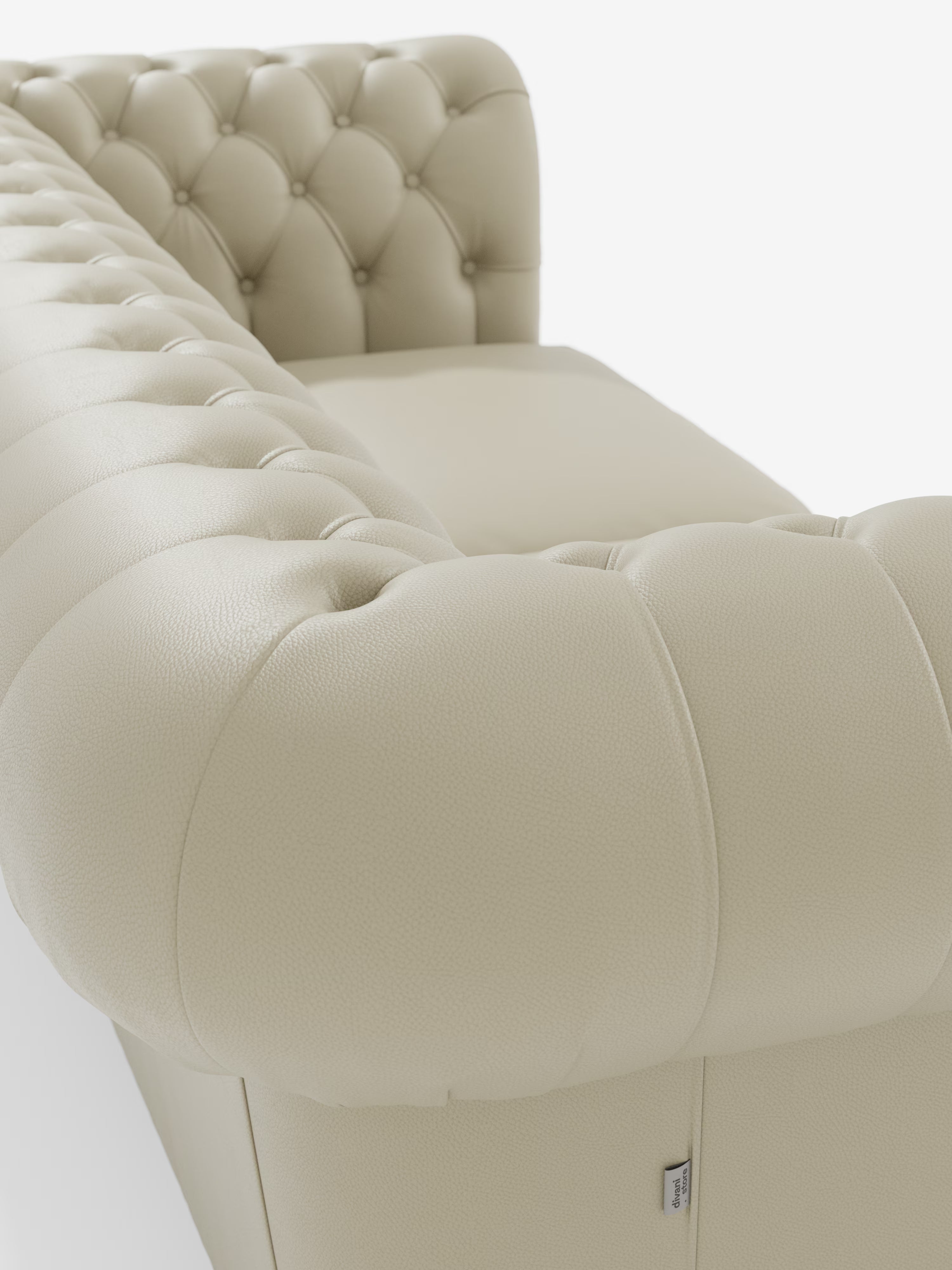 Primo piano di un Chester color crema – Divano Chesterfield in vera pelle spessorata a 2 e 3 posti di Divani.Store, caratterizzato da un rivestimento in vera pelle trapuntata con bottoni decorativi lungo lo schienale e braccioli arrotondati. L'immagine mette in risalto la morbida consistenza del tessuto ed esalta l'eleganza intramontabile e artigianale di questo classico Made in Italy.