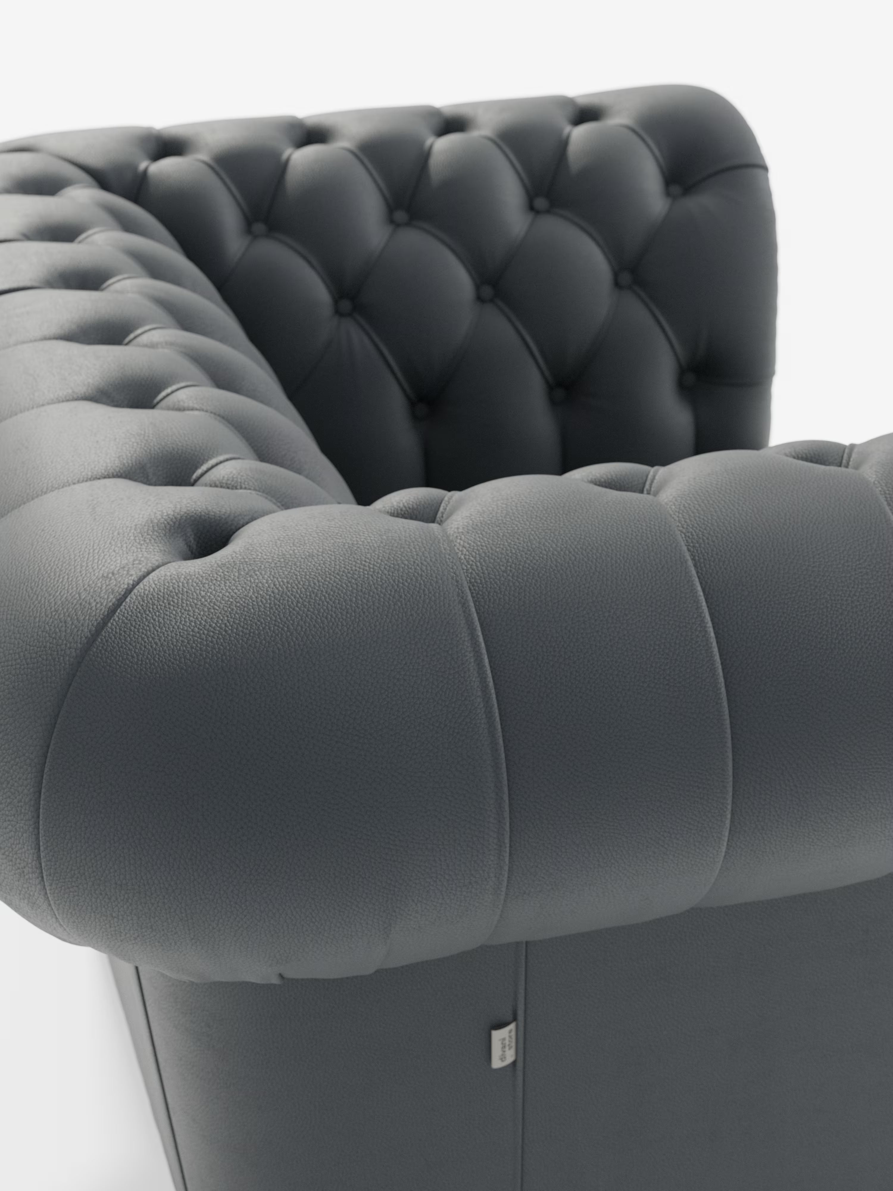 Primo piano della poltrona Chester in vera pelle spessorata con capitonné artigianale di Divani.Store, che mette in risalto i braccioli e lo schienale in pelle grigio scuro. Spiccano la profonda trapuntatura a bottoni e l'imbottitura morbida e arrotondata, con la lussuosa trama della pelle e le cuciture precise chiaramente visibili, a testimonianza della maestria artigianale che contraddistingue gli arredi di Divani.Store. Lo sfondo è bianco a tinta unita.