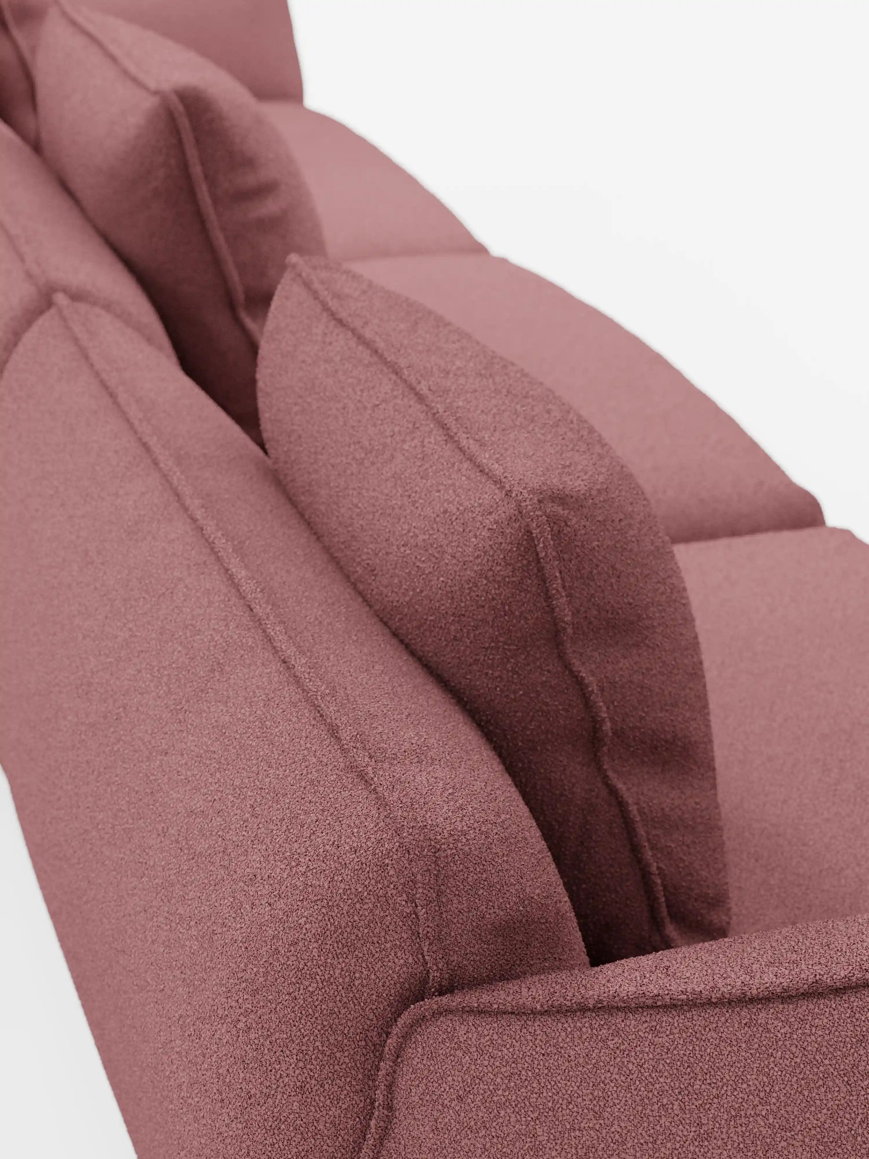 Vista di profilo del divano modulare a 3 posti Nimbus di Divani.Store, rivestito in morbido tessuto T33 color malva, resistente alle macchie e con una trama effetto cotone. Il design contemporaneo e minimalista del divano è messo in risalto da tre cuscini dello schienale disposti con cura e da cuscini di seduta dall’aspetto visibilmente soffice, che risaltano su uno sfondo bianco a tinta unita.