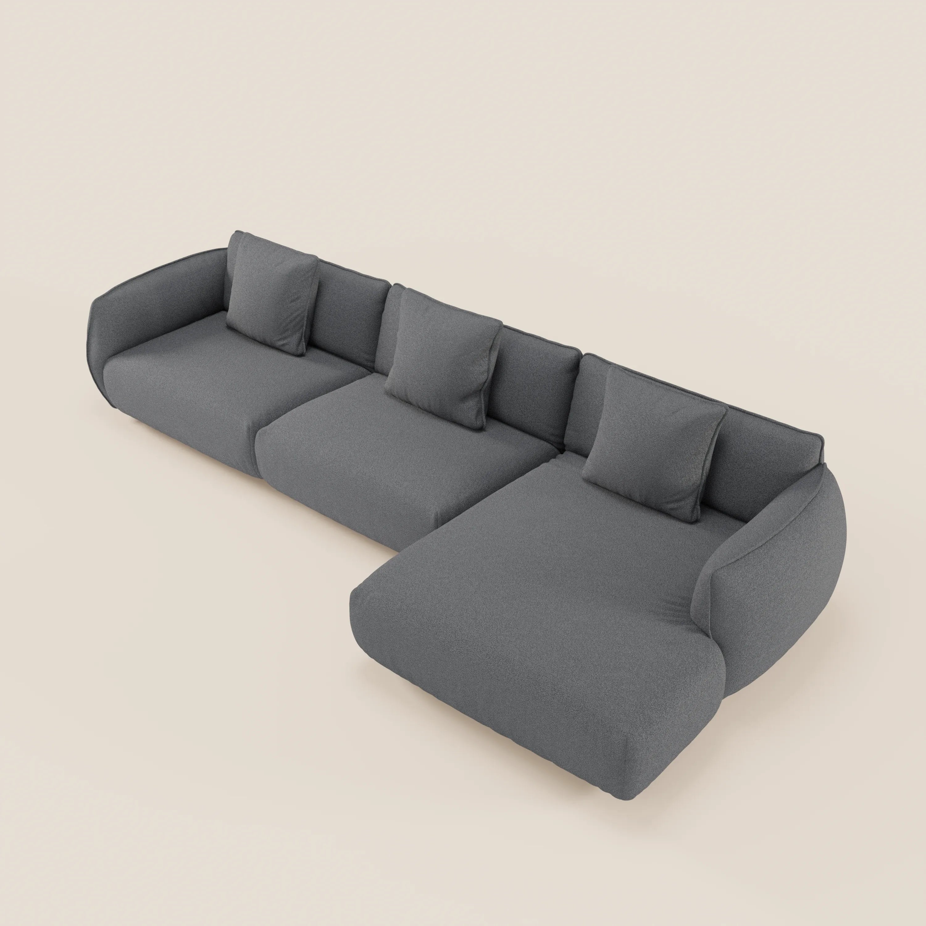 Il divano Nimbus angolare con penisola componibile di Divani.Store, in tessuto grigio scuro effetto cotone smacchiabile, ha tre cuscini di seduta, quattro cuscini di schienale coordinati e una chaise lounge a destra su uno sfondo beige chiaro.