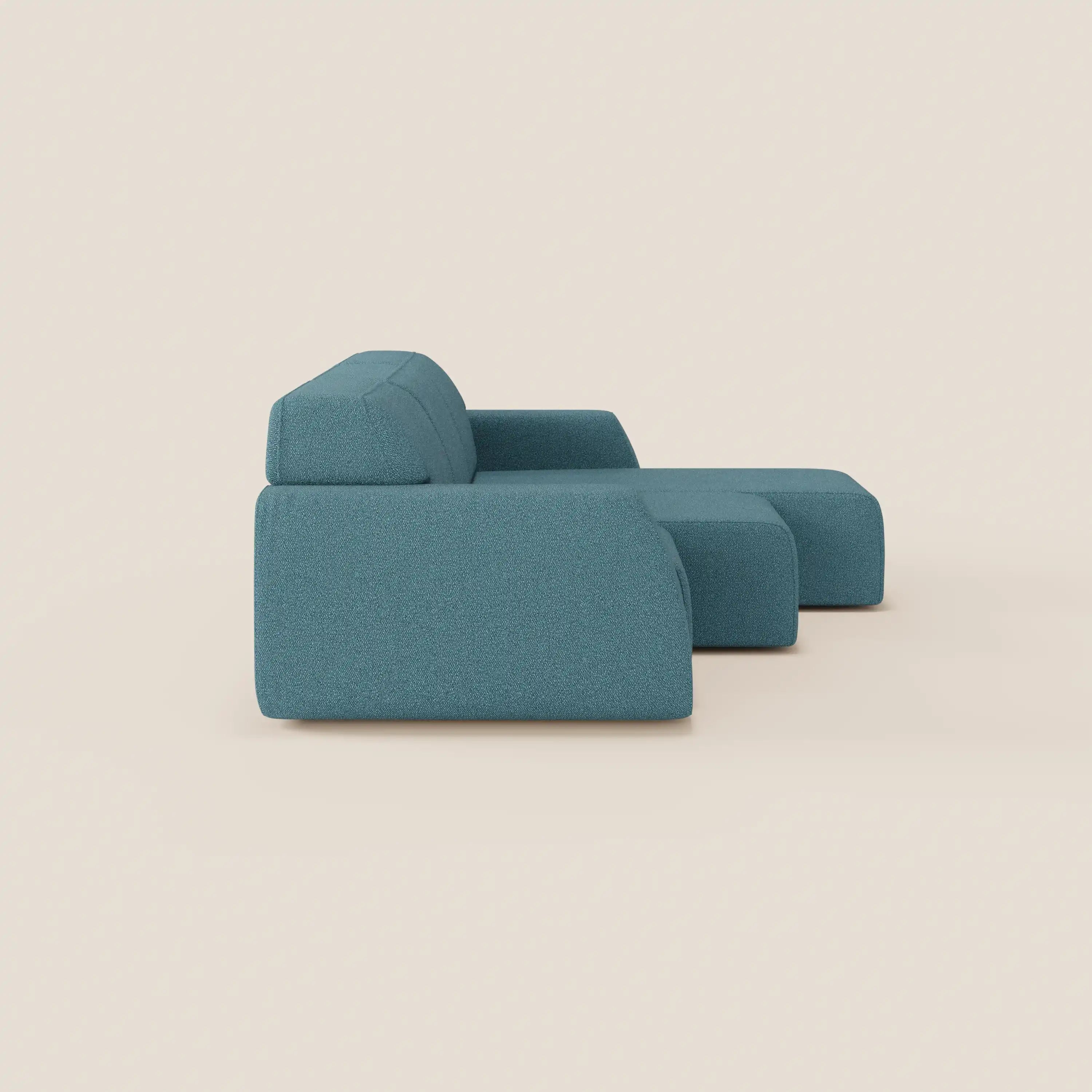 The Divani.Store Orbit divano angolare con penisola reversibile, tutte le sedute allungabili, in tessuto smacchiabile effetto cotone T33 teal, presenta linee pulite, schienale basso e cuscini spessi su fondo beige chiaro.