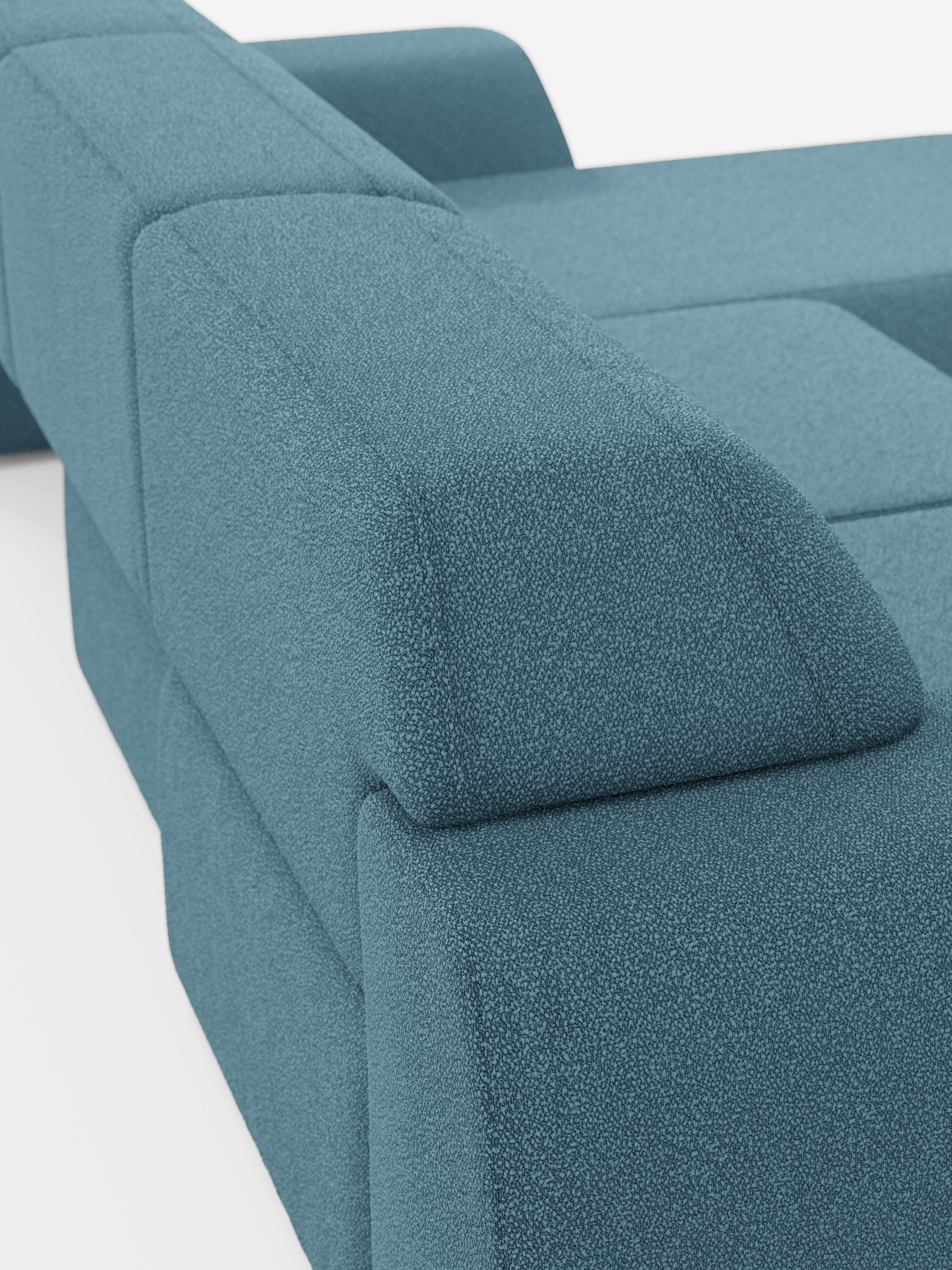 Primo piano del divano angolare Orbit con penisola reversibile e tutte le sedute allungabili in tessuto smacchiabile effetto cotone T33 di Divani.Store, rivestito in tessuto cotone testurizzato effetto verde acqua. L'immagine mette in risalto le linee pulite e le forme geometriche di questo moderno divano componibile, concentrandosi sui braccioli e sullo schienale con imbottitura morbida e strutturata e design minimalista su uno sfondo bianco.