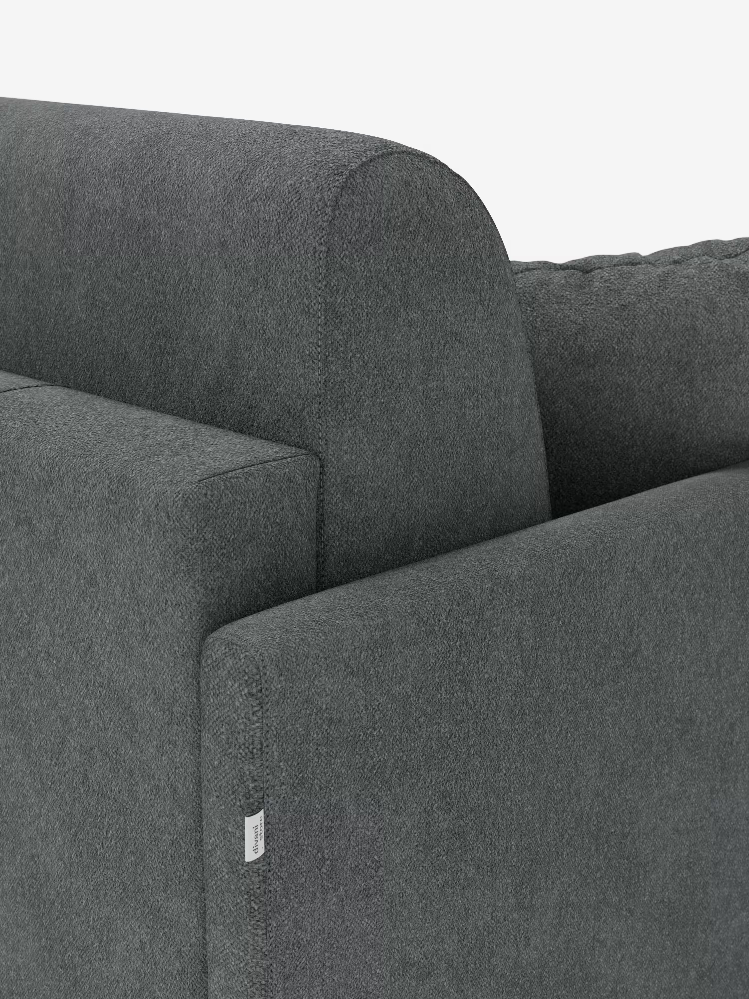 Primo piano del divano letto Tommy a 2 e 3 posti matrimoniale di Divani.Store in grigio scuro, che mette in risalto il design moderno con linee pulite sui braccioli e sullo schienale. È chiaramente visibile la trama del tessuto smacchiabile T33 simil cotone, mentre vicino alla cucitura inferiore è applicata una piccola etichetta bianca. Lo sfondo bianco a tinta unita mette in risalto la struttura del divano e il rivestimento rimovibile al 100%.