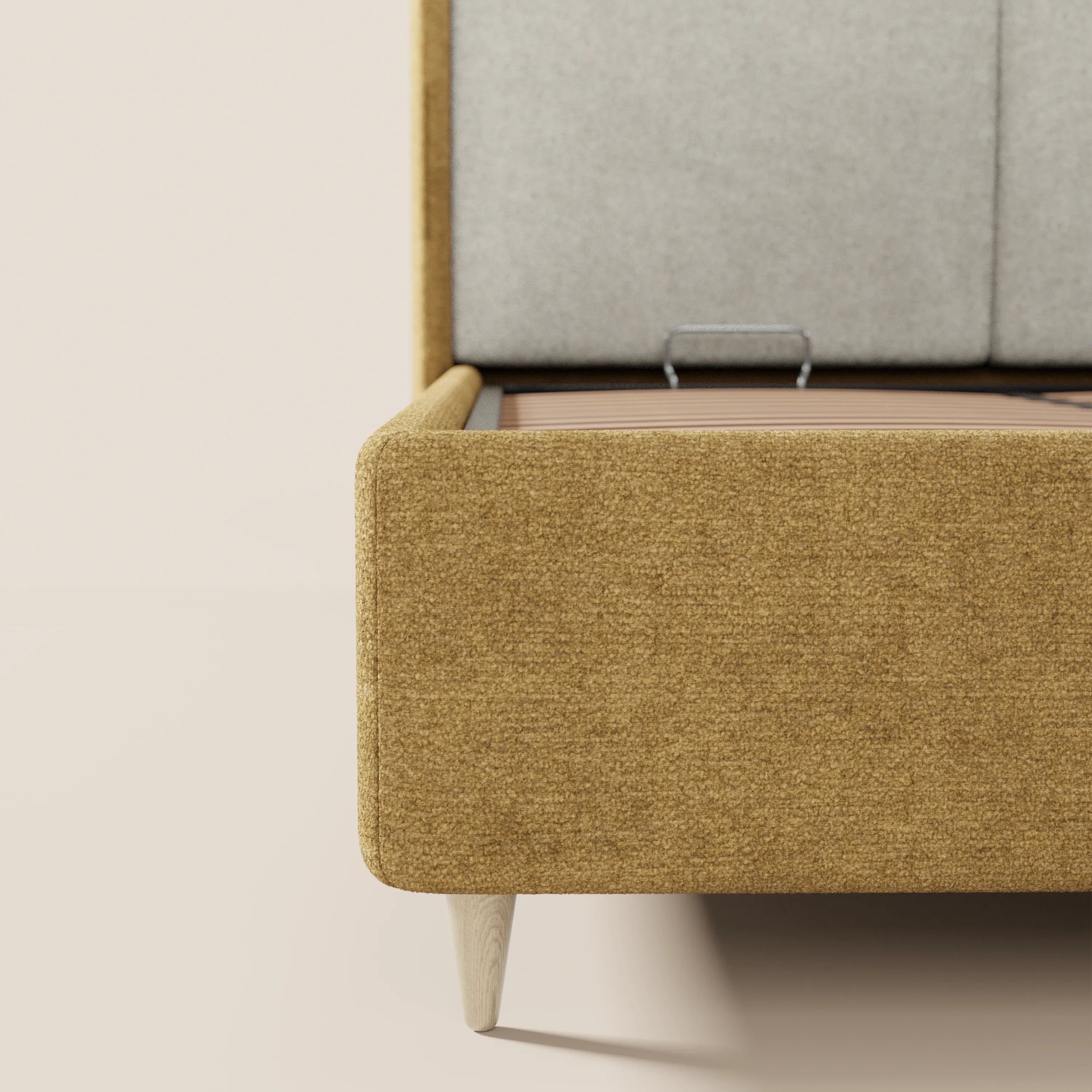 Primo piano su VALKIRIA di Letti.store: un letto imbottito bicolore con contenitore, caratterizzato da gambe in legno chiaro, rivestimento giallo senape e una testiera curva grigio chiaro con cuscini imbottiti sullo schienale, per un design italiano dal tocco morbido.