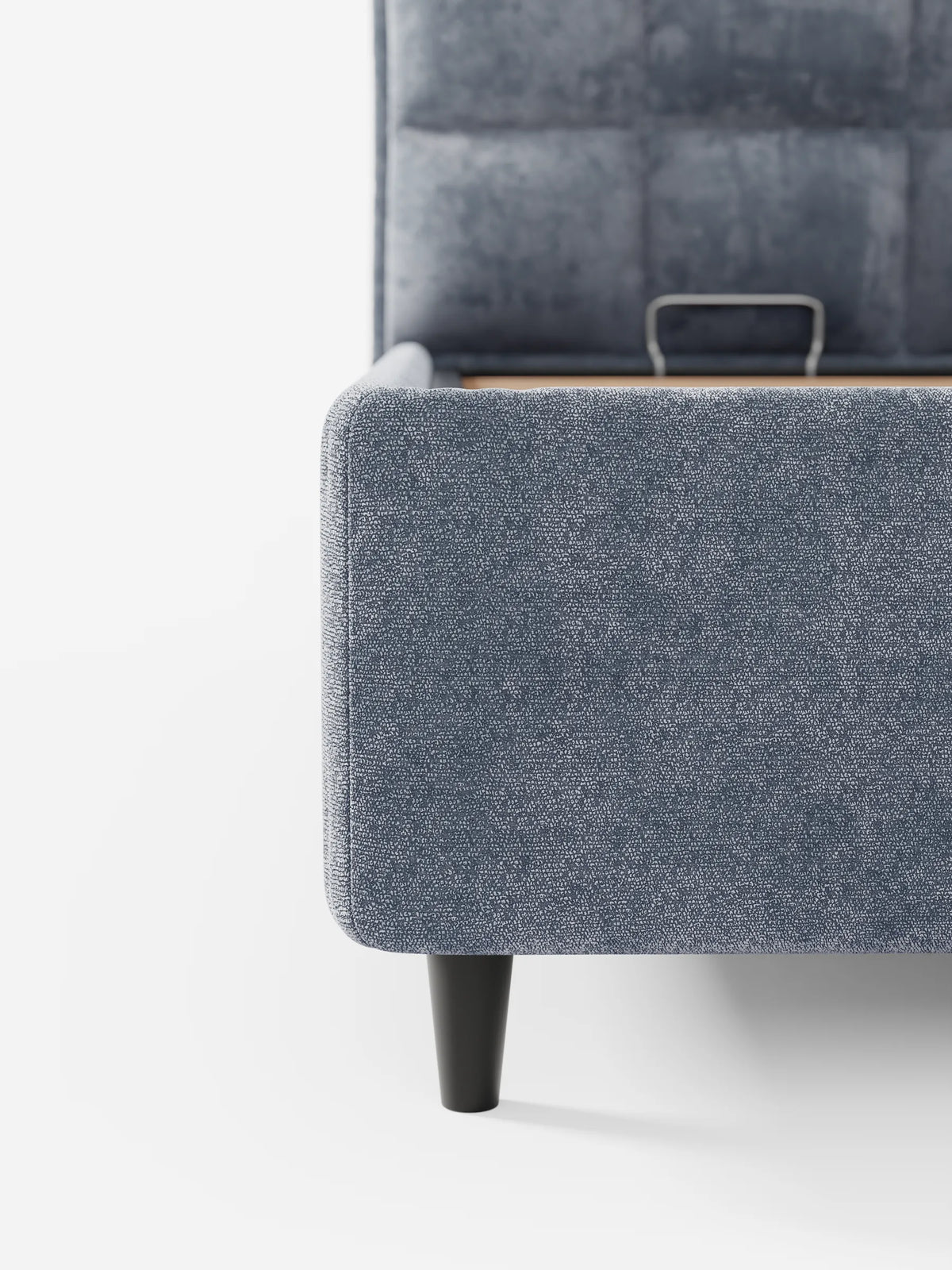 Il letto imbottito AURO con contenitore e testiera capitonné alta in ciniglia Oeko-Tex® è un letto imbottito realizzato in tessuto testurizzato color blu ardesia, con una testiera alta capitonné, una base con contenitore a vista e gambe affusolate scure su sfondo bianco.