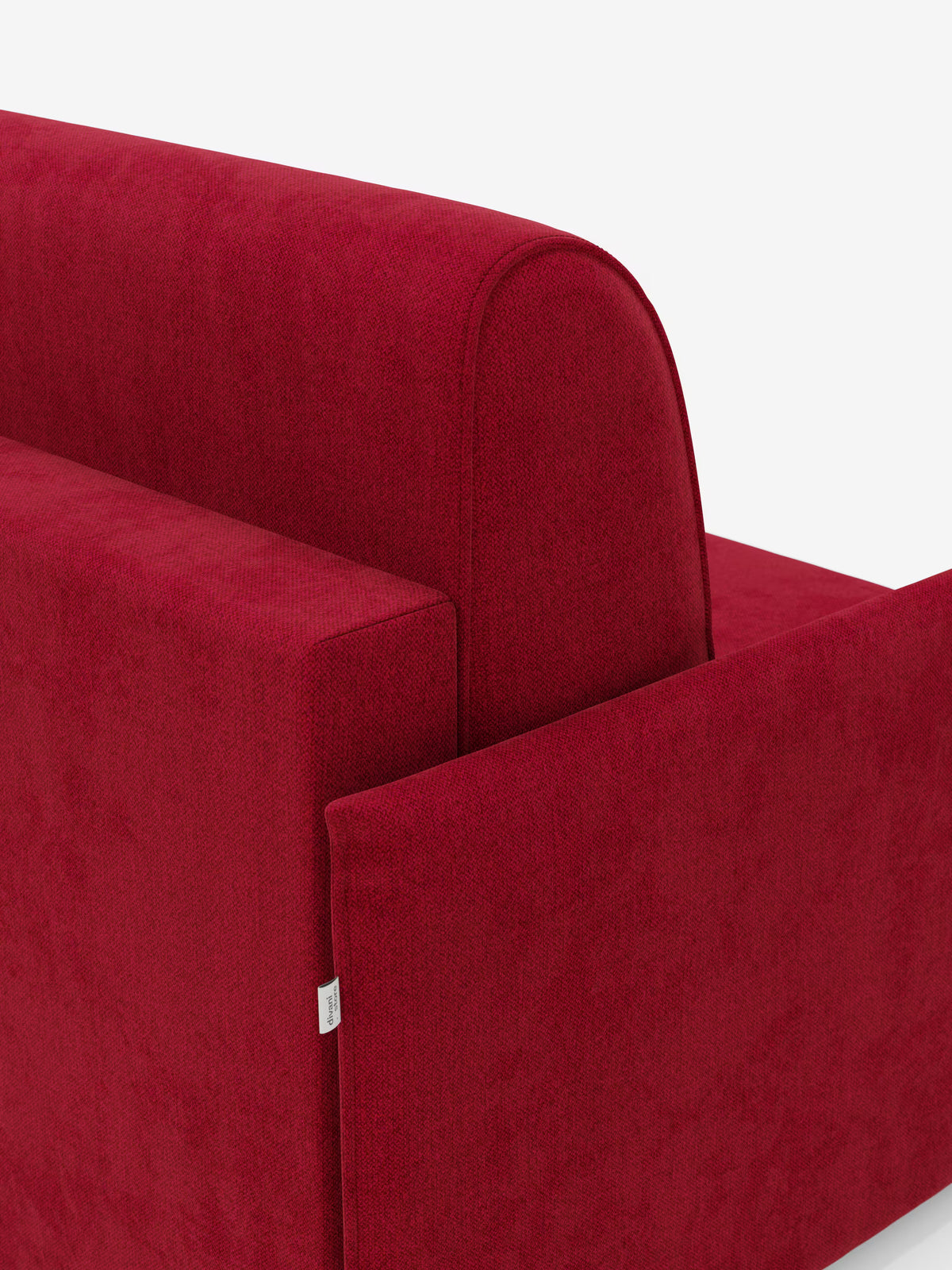 Un primo piano della poltrona letto compatta Evans con materasso di Divani.Store, rivestita in tessuto T23 rosso intenso e resistente alle macchie, su sfondo bianco. L'immagine mette in risalto le sue linee pulite, la forma squadrata, il rivestimento dalla texture morbida e mostra una piccola etichetta in tessuto in corrispondenza della cucitura.