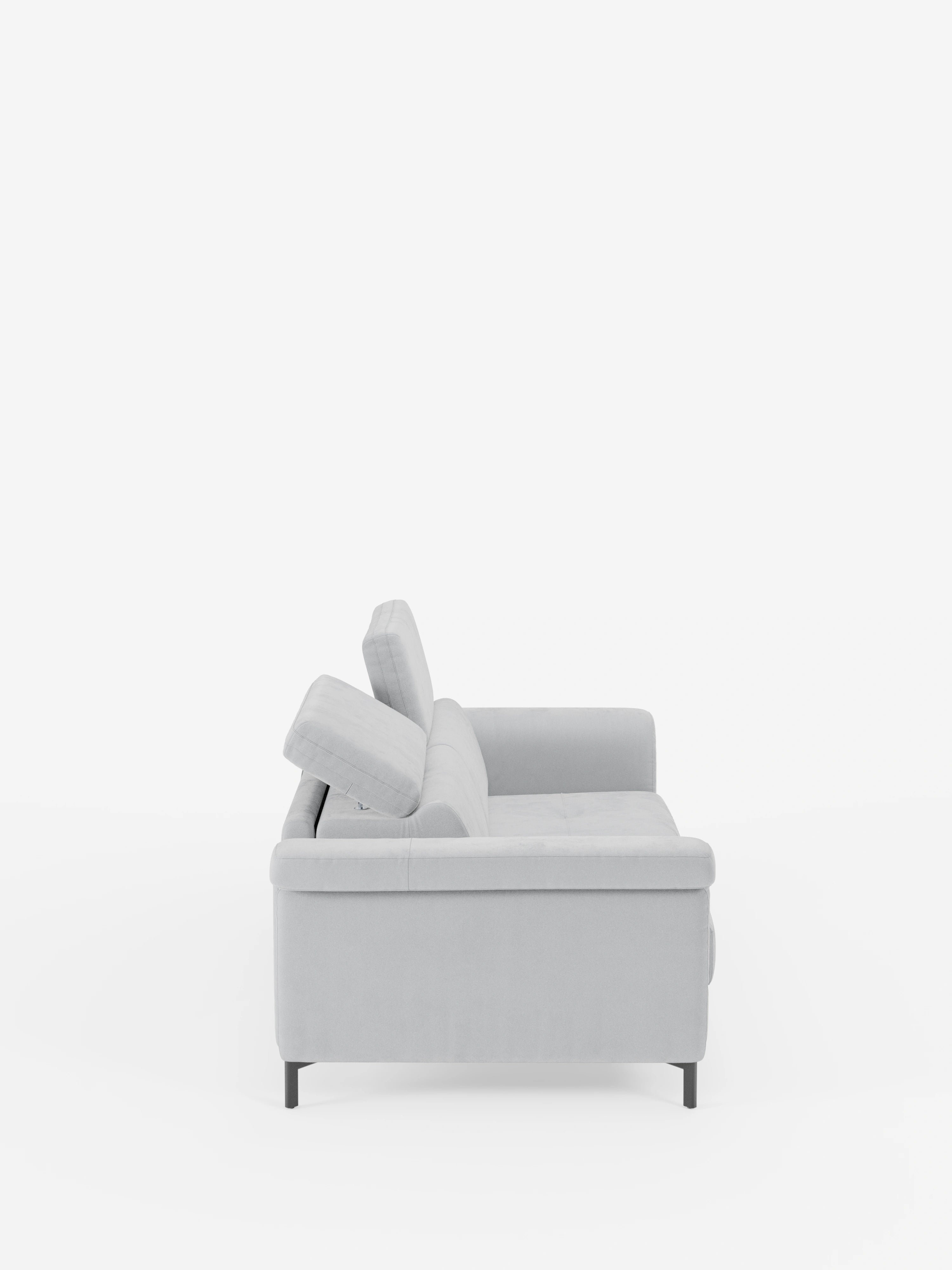 Un moderno divano letto di design Capri di Divani.Store, rivestito in raffinato tessuto effetto velluto grigio chiaro resistente alle macchie (T30), è ripreso di profilo su uno sfondo bianco a tinta unita. Questo divano presenta braccioli dritti, cuscini dello schienale angolati con poggiatesta regolabili, gambe alte e sottili di colore nero e linee pulite e minimaliste, che rispecchiano la raffinata manifattura italiana.