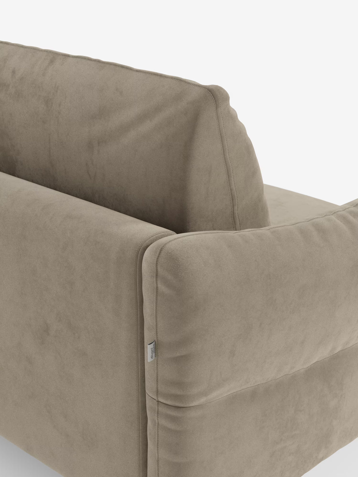 Primo piano dello schienale e del bracciolo del divano letto Dalia a 2, 3 e 4 posti con materasso H18 di Divani.Store, rivestito in moderno tessuto vellutino T30 antimacchia in una tonalità taupe. Il morbido e soffice rivestimento e una piccola etichetta in tessuto cucita sono visibili su uno sfondo bianco, mettendo in risalto la trama del divano e il suo design minimalista e contemporaneo.