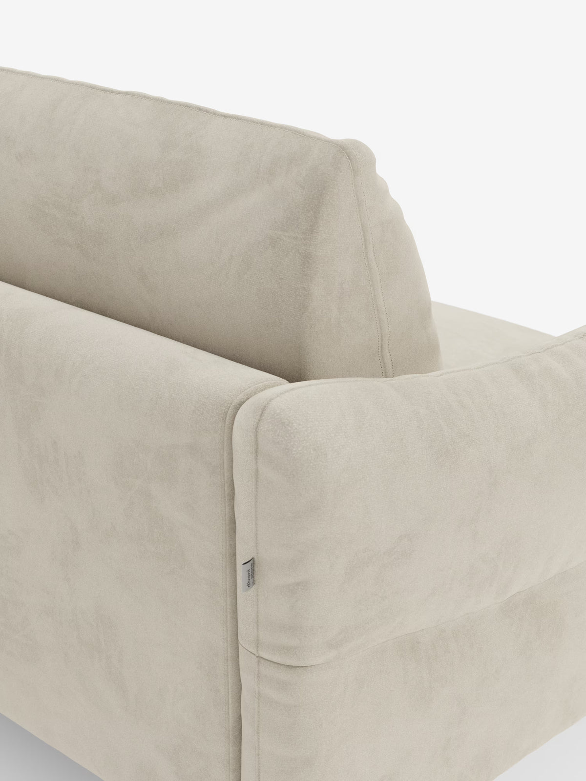 Un primo piano del divano letto Dalia di Divani.Store, disponibile nelle versioni a 2, 3 e 4 posti con materasso H18 e rivestito in moderno velluto T30 antimacchia, ne mette in risalto lo schienale e i braccioli morbidi. La foto mette in risalto la consistenza morbida e vellutata, i delicati dettagli delle cuciture e una piccola etichetta in tessuto sul lato. Lo sfondo è bianco.