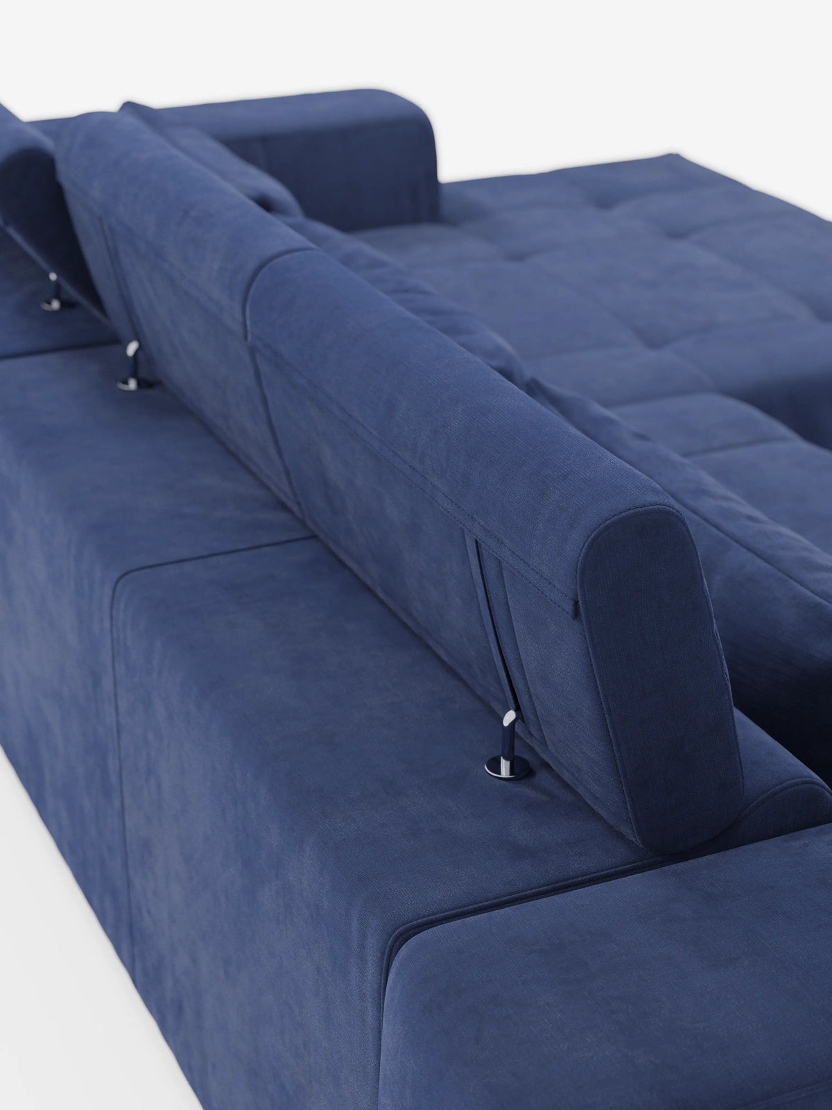 Un primo piano del divano angolare Monarch con penisola e sistema Relax Elettrico per l'allungamento delle sedute di Divani.Store, rivestito in morbido tessuto T31 blu intenso e resistente alle macchie, è ripreso di profilo dalla parte posteriore. I poggiatesta reclinabili regolabili sono fissati con supporti metallici a vista, mentre la morbida superficie di seduta si estende fino a formare una chaise longue. Sfondo bianco.