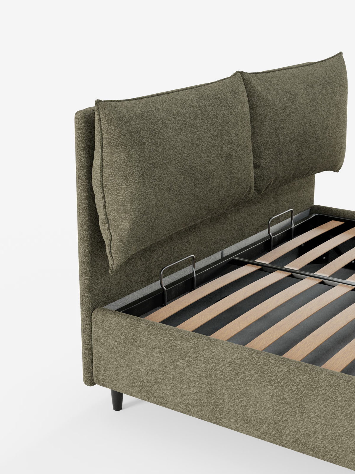 Un primo piano del letto imbottito ZAYRON con contenitore e morbidi cuscini regolabili di Letti.store mette in risalto la testiera imbottita in verde oliva, certificata Oeko-Tex®, con due grandi e soffici cuscini regolabili. Le doghe in legno che sostengono il materasso sono visibili e il letto dal design moderno poggia su corte gambe nere su uno sfondo bianco a tinta unita.