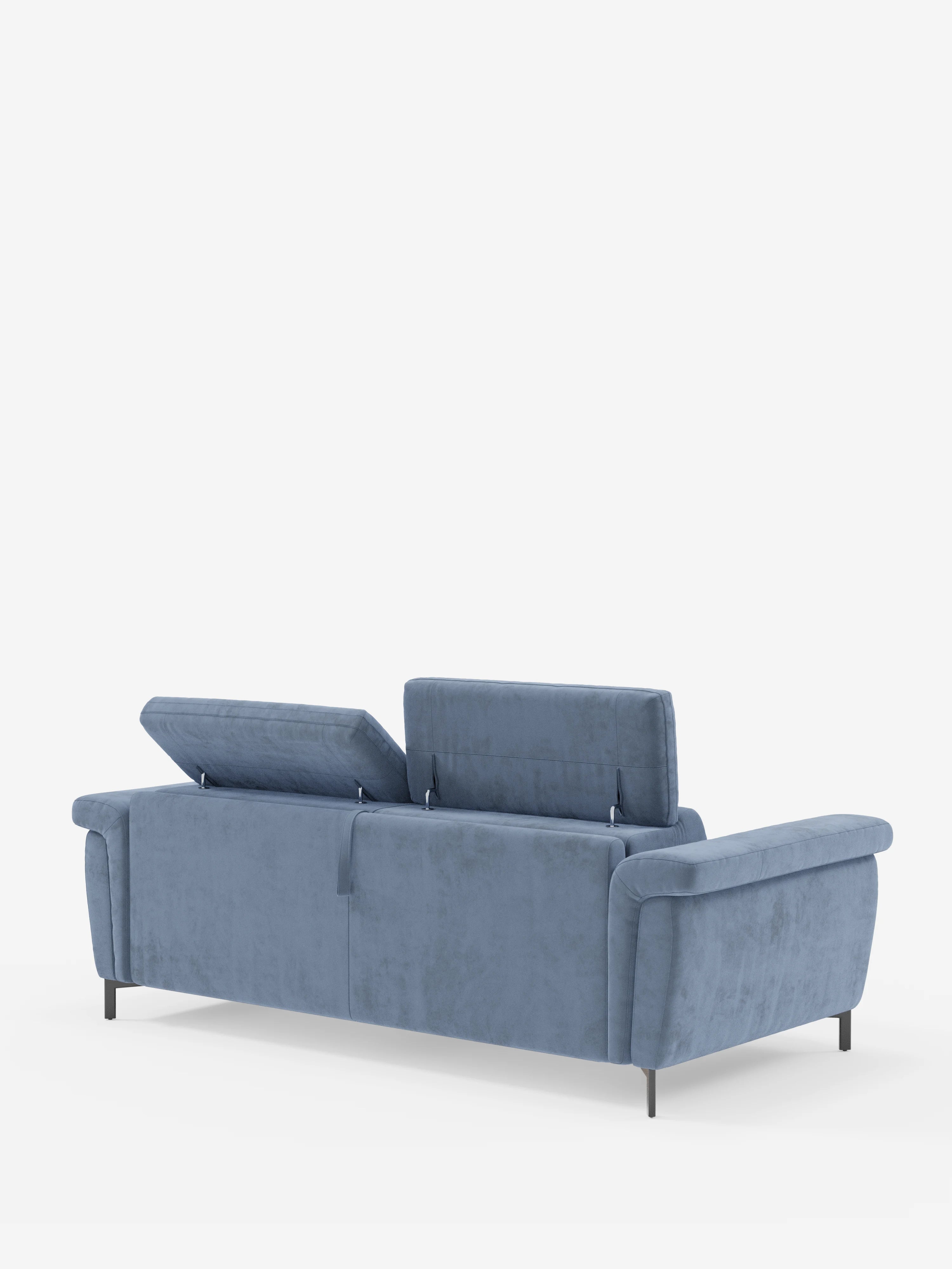 Il divano letto di design Capri con piedini alti di Divani.Store è raffigurato di retro, rivestito in raffinato tessuto effetto velluto smacchiabile T30 di colore blu. Due dei tre poggiatesta reclinabili sono sollevati, mentre il terzo rimane in posizione orizzontale. Il divano moderno, caratterizzato da sottili gambe nere, è posto su uno sfondo bianco a tinta unita.