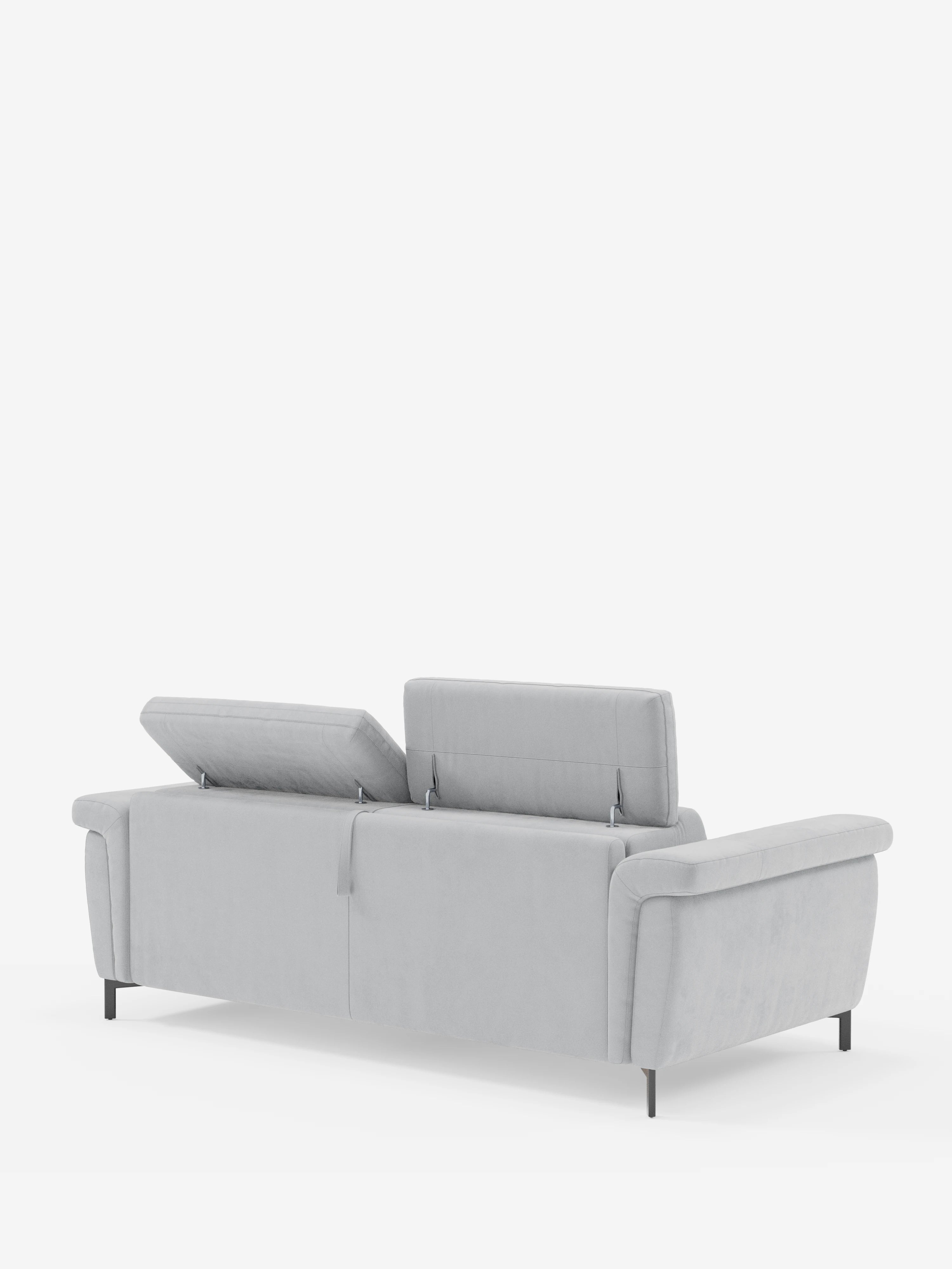 Il divano letto Capri di design, in grigio chiaro, di Divani.Store è ripreso di retro, con le sue sottili gambe nere e i tre poggiatesta regolabili: due rialzati e uno piatto. Il divano, rivestito in raffinato tessuto effetto velluto smacchiabile T30, risalta su uno sfondo bianco a tinta unita.