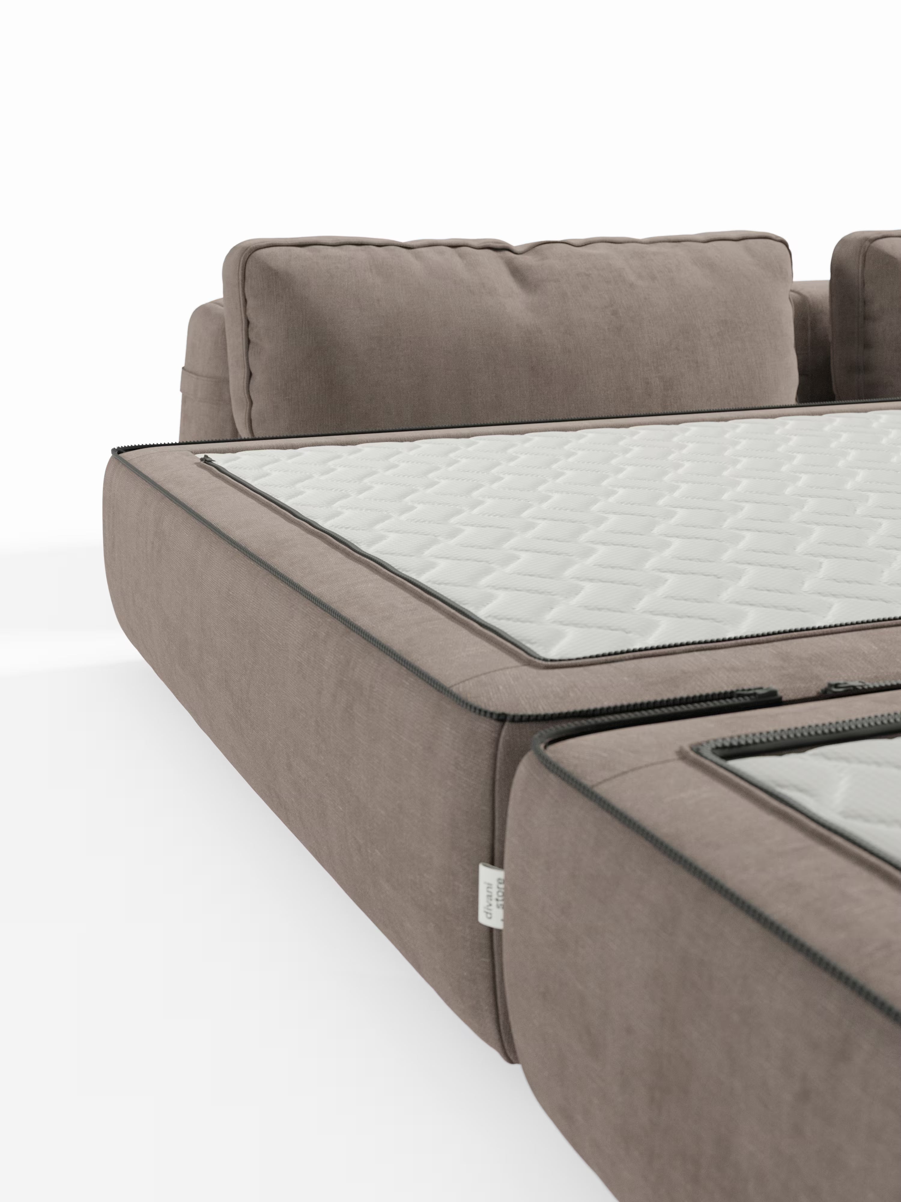 Primo piano del divano letto matrimoniale Rift di Divani.Store, qui raffigurato in tessuto color taupe con una sezione aperta tramite cerniera che ne rivela il materasso trapuntato in memory foam T31 alto 22 cm. L’immagine mette in risalto il design modulare del divano con schienali mobili, evidenziandone la doppia funzione di elegante divano letto a 2 o 3 posti. Lo sfondo bianco a tinta unita esalta la trama del tessuto e i dettagli curati.