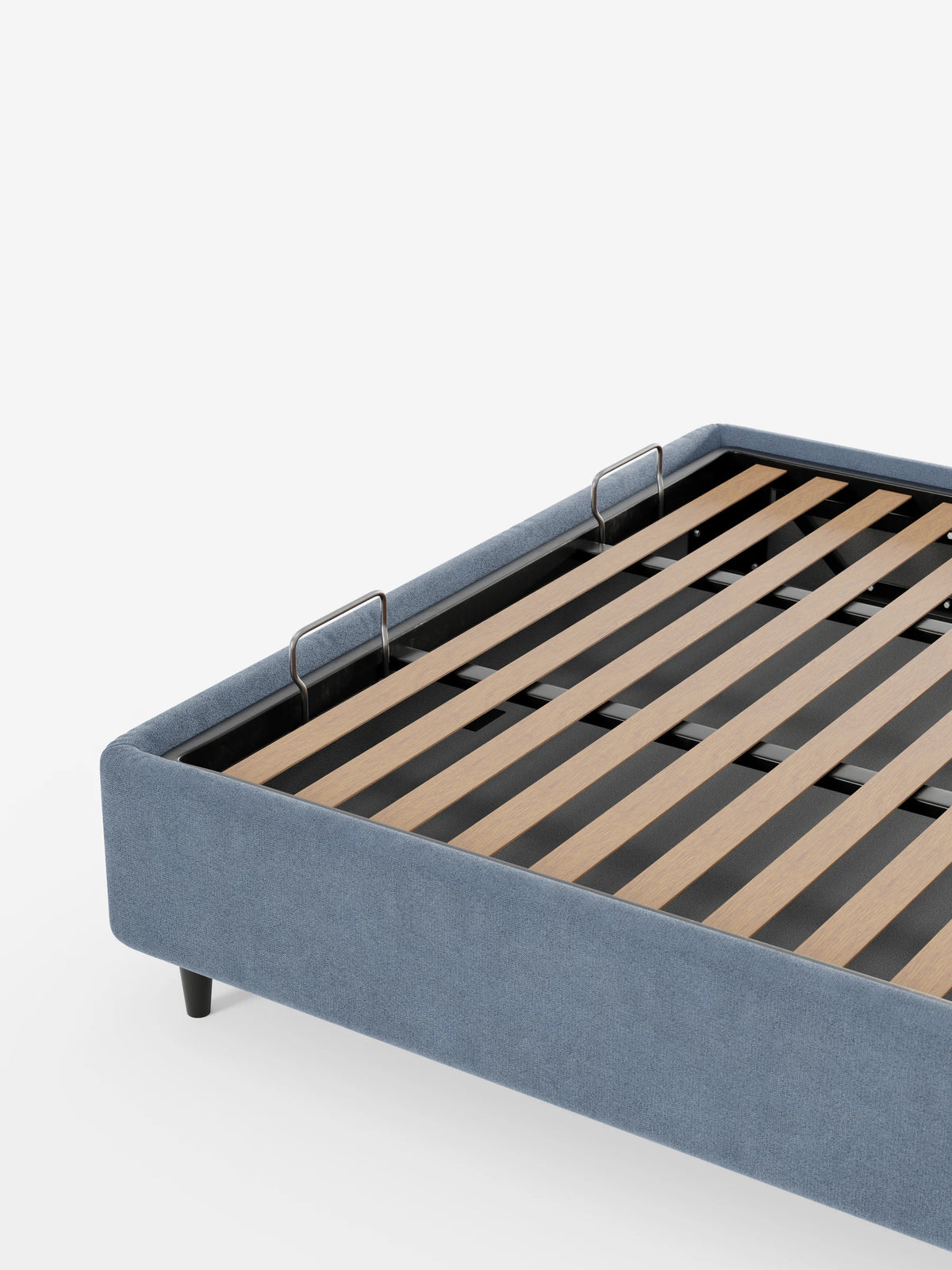 Un letto sommier imbottito ERON con vano contenitore in tessuto impermeabile certificato Oeko-Tex, di colore blu, spicca su uno sfondo bianco; presenta una base a doghe rialzata e due piccole maniglie in metallo che consentono l’accesso al vano contenitore.