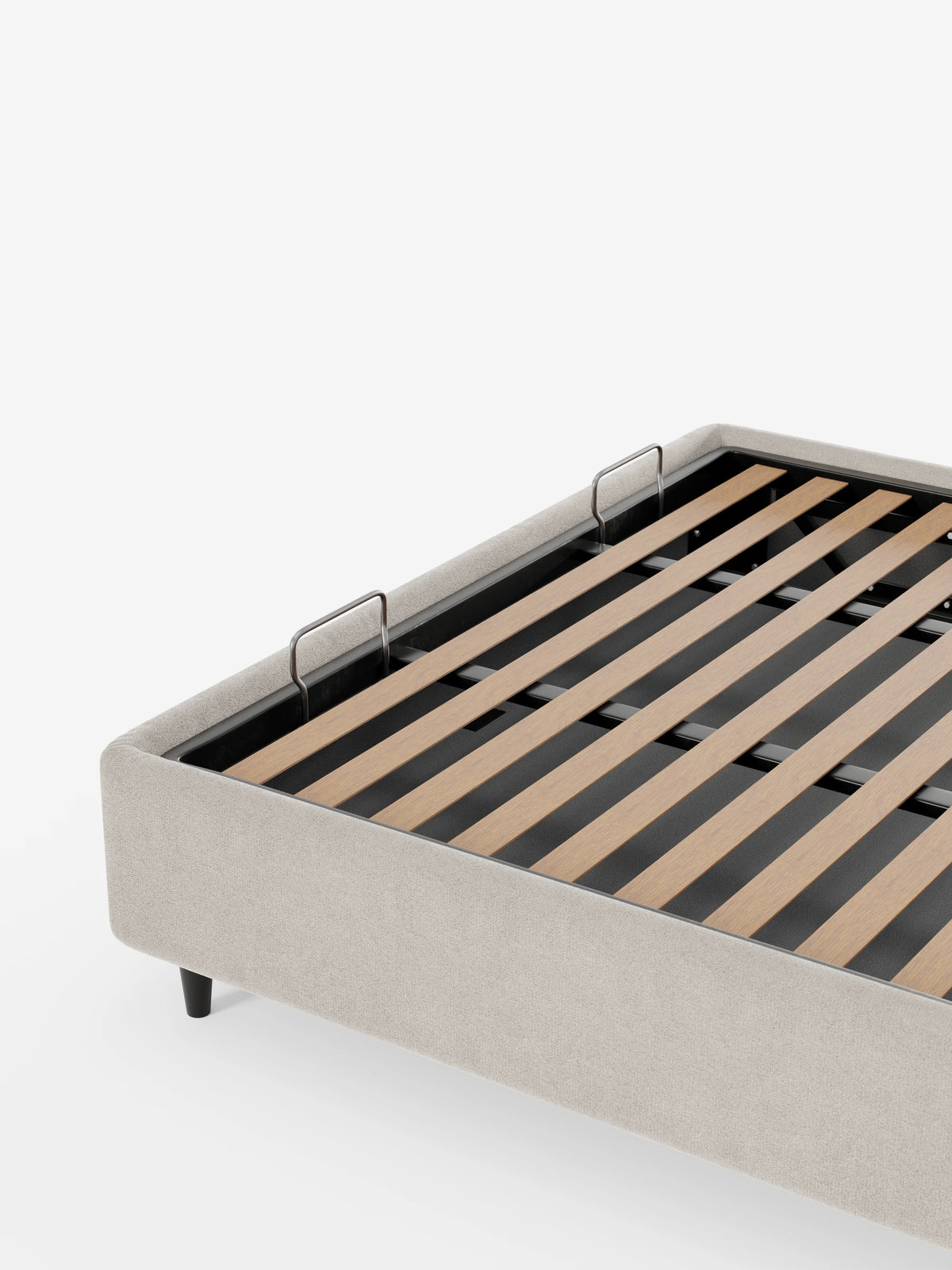 Il letto sommier imbottito ERON con contenitore in tessuto impermeabile certificato Oeko-Tex è una struttura letto imbottita color beige chiaro con base a doghe, supporti metallici per il materasso e piccoli piedini neri su uno sfondo bianco a tinta unita.