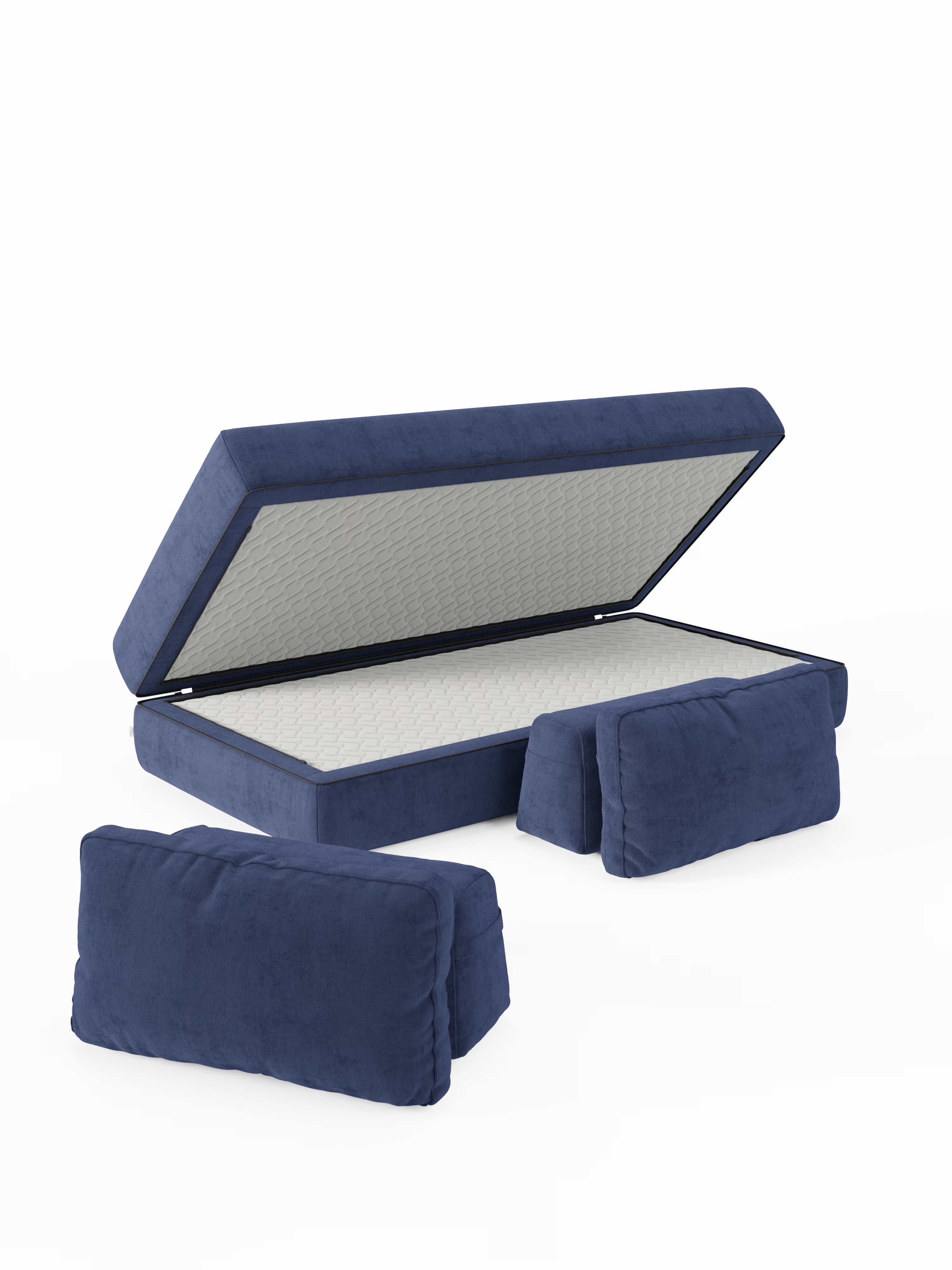 Il divano letto matrimoniale blu Rift a 2 e 3 posti con schienali mobili di Divani.Store è raffigurato con la seduta sollevata per mostrare lo spazio di stivaggio interno. Due cuscini blu coordinati per lo schienale sono posizionati davanti, su uno sfondo bianco a tinta unita.