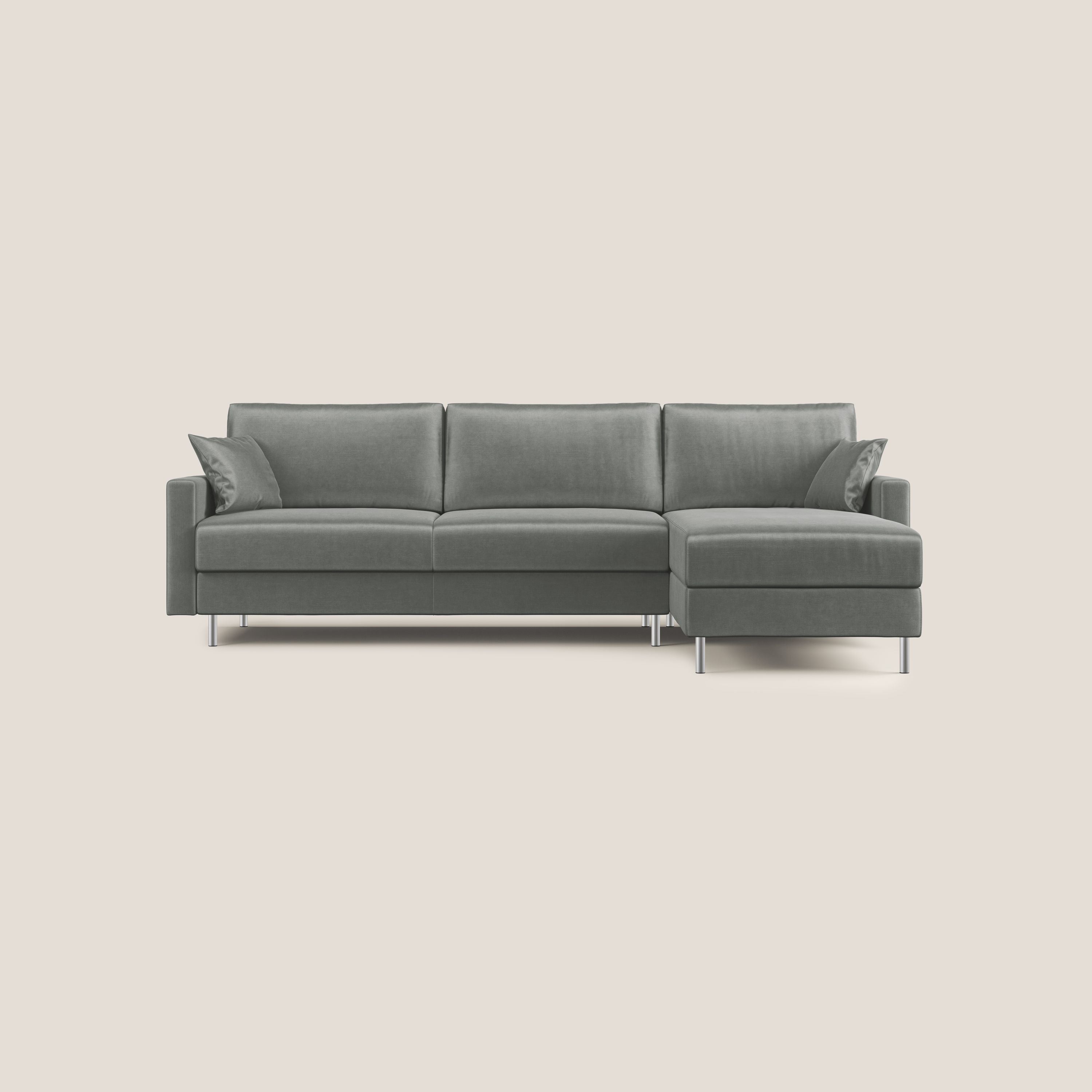 Il divano letto angolare Andromeda in velluto morbido impermeabile T01 grigio chiaro di Divani.Store è caratterizzato da linee pulite, gambe in metallo e due cuscini coordinati. La poltrona si trova alla destra dell'osservatore, su uno sfondo beige.