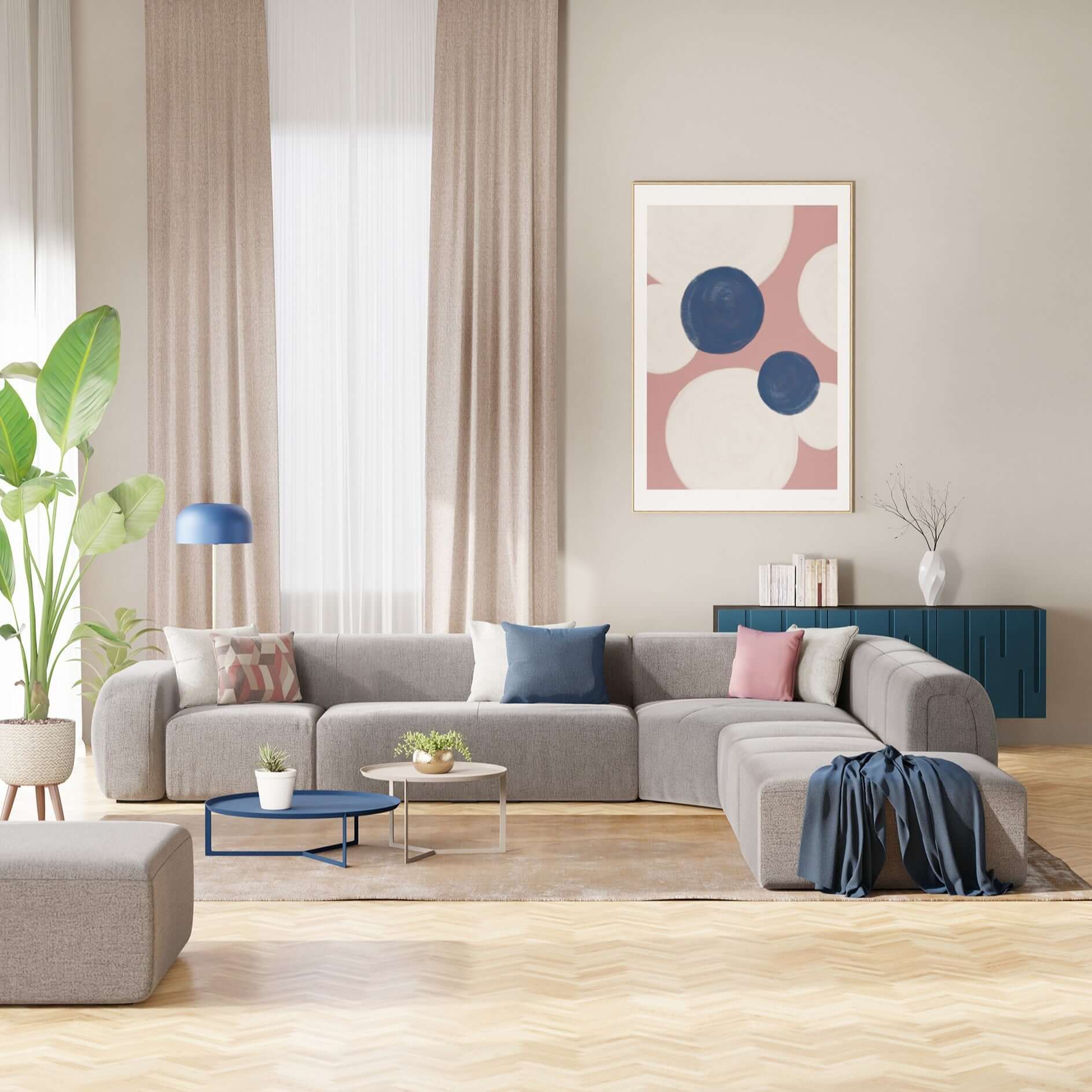 Un soggiorno moderno con il divano BonBon angolare componibile e modulare in tessuto smacchiabile T23 grigio di Divani.Store, con cuscini colorati, tappeto beige, tavolini rotondi, pianta alta, lampada blu, opere d'arte e una credenza blu.