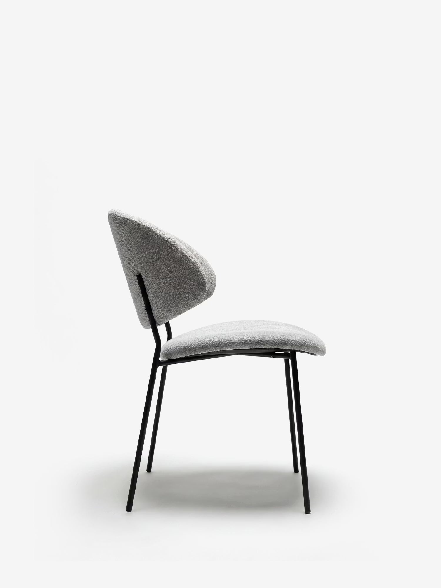 La sedia Bruma di Divani.Store è caratterizzata da un elegante tessuto goffrato, uno schienale avvolgente e gambe in metallo nero. Il design minimalista di questa sedia moderna ne esalta lo stile contemporaneo, perfetto per ogni ambiente.