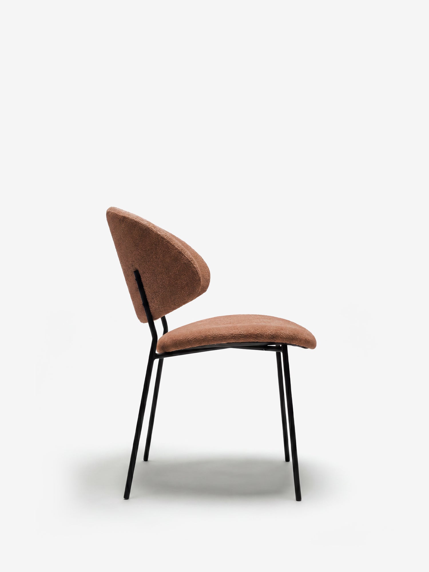 La Bruma di Divani.Store è una sedia realizzata in elegante tessuto marrone goffrato, con schienale avvolgente e gambe sottili in metallo nero, dal design minimalista e contemporaneo, perfetta per gli ambienti moderni.
