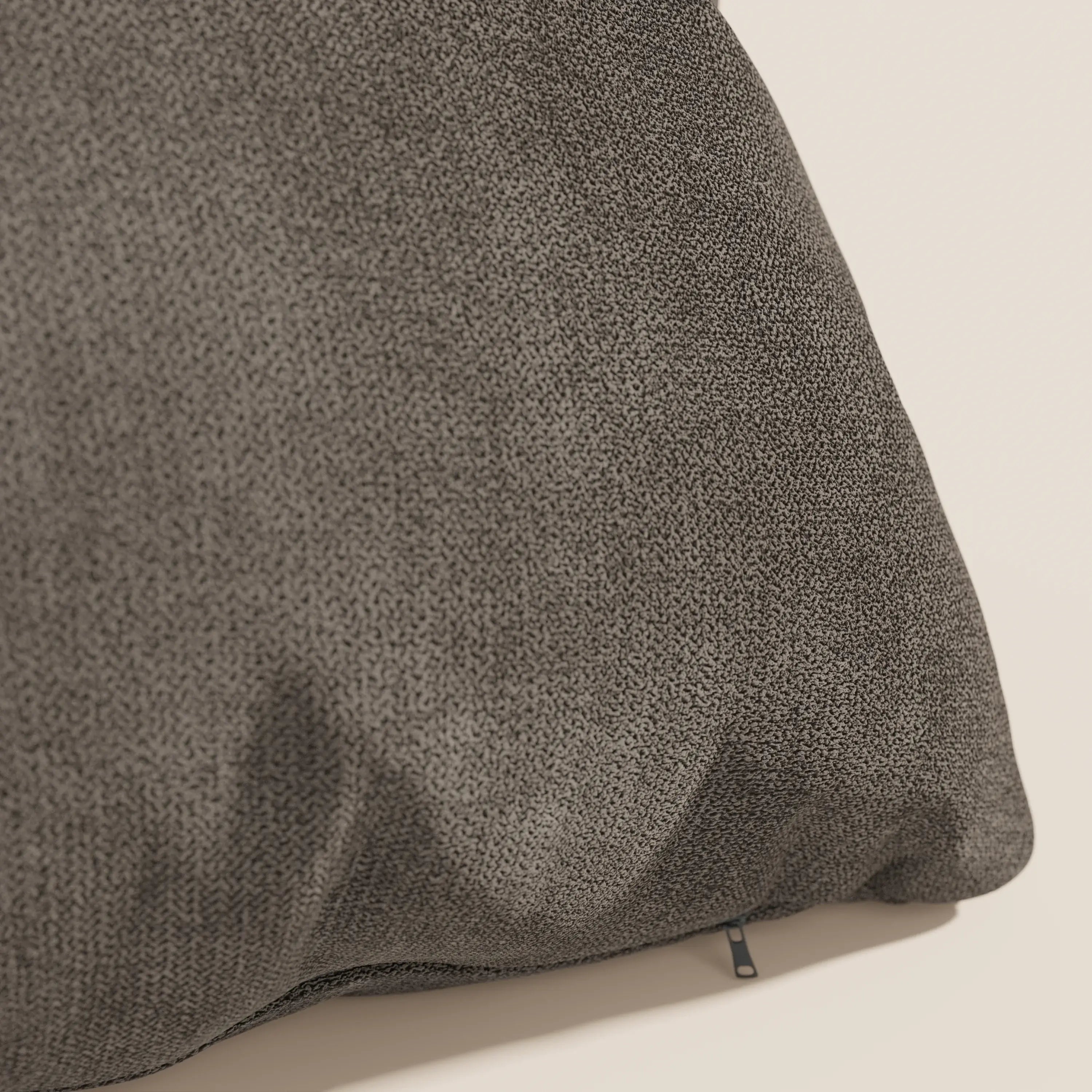 Primo piano del cuscino Destiny di Divani.Store, presentato in impermeabile T02 marrone. Il tessuto morbido e strutturato, con cerniera a vista, si staglia su uno sfondo beige, con lievi pieghe che ne evidenziano la morbidezza.