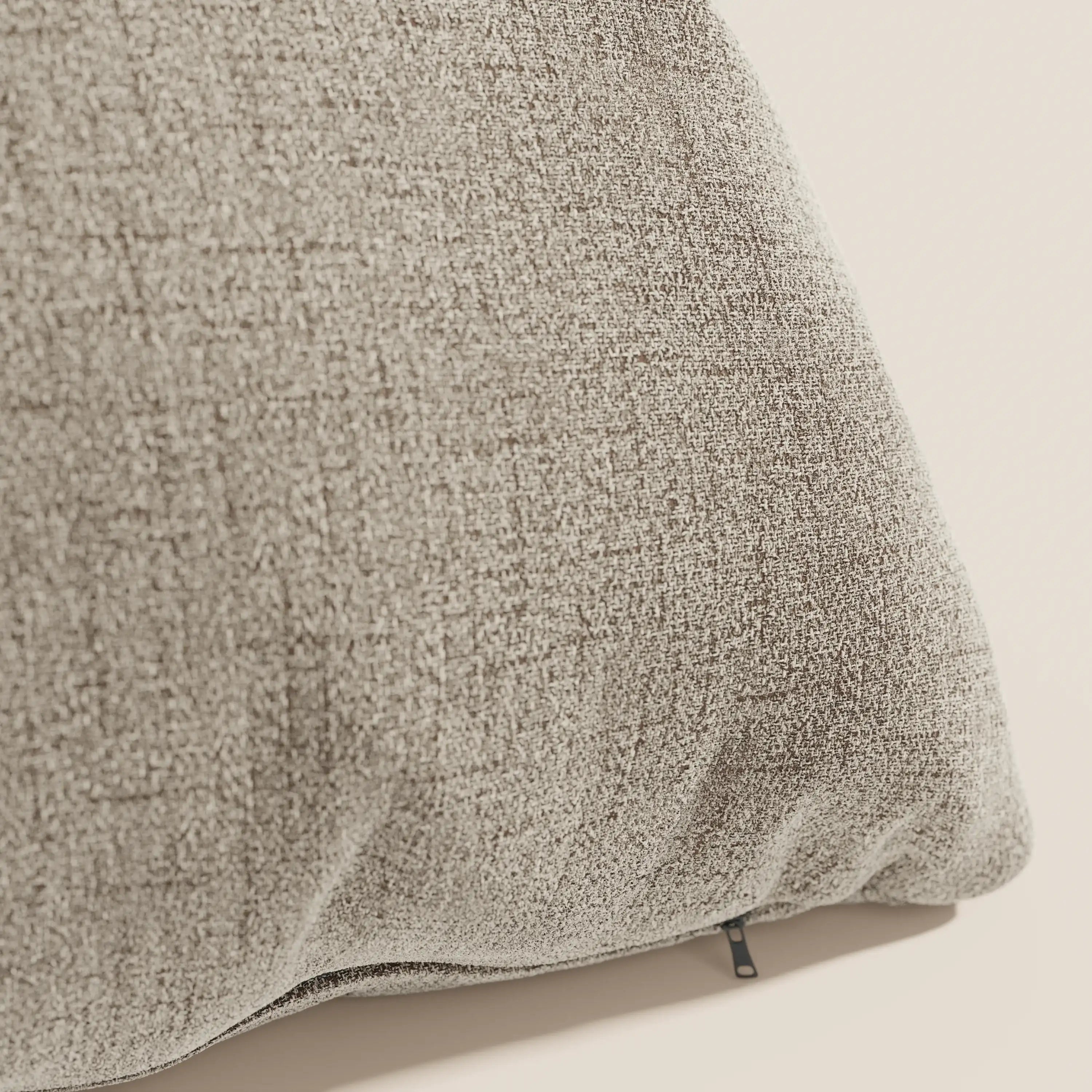 Primo piano del cuscino Felis di Divani.Store, disponibile in tessuto morbido impermeabile T03 beige con trama delicata e zip nera sul bordo per fodera removibile. Sfondo chiaro e semplice.
