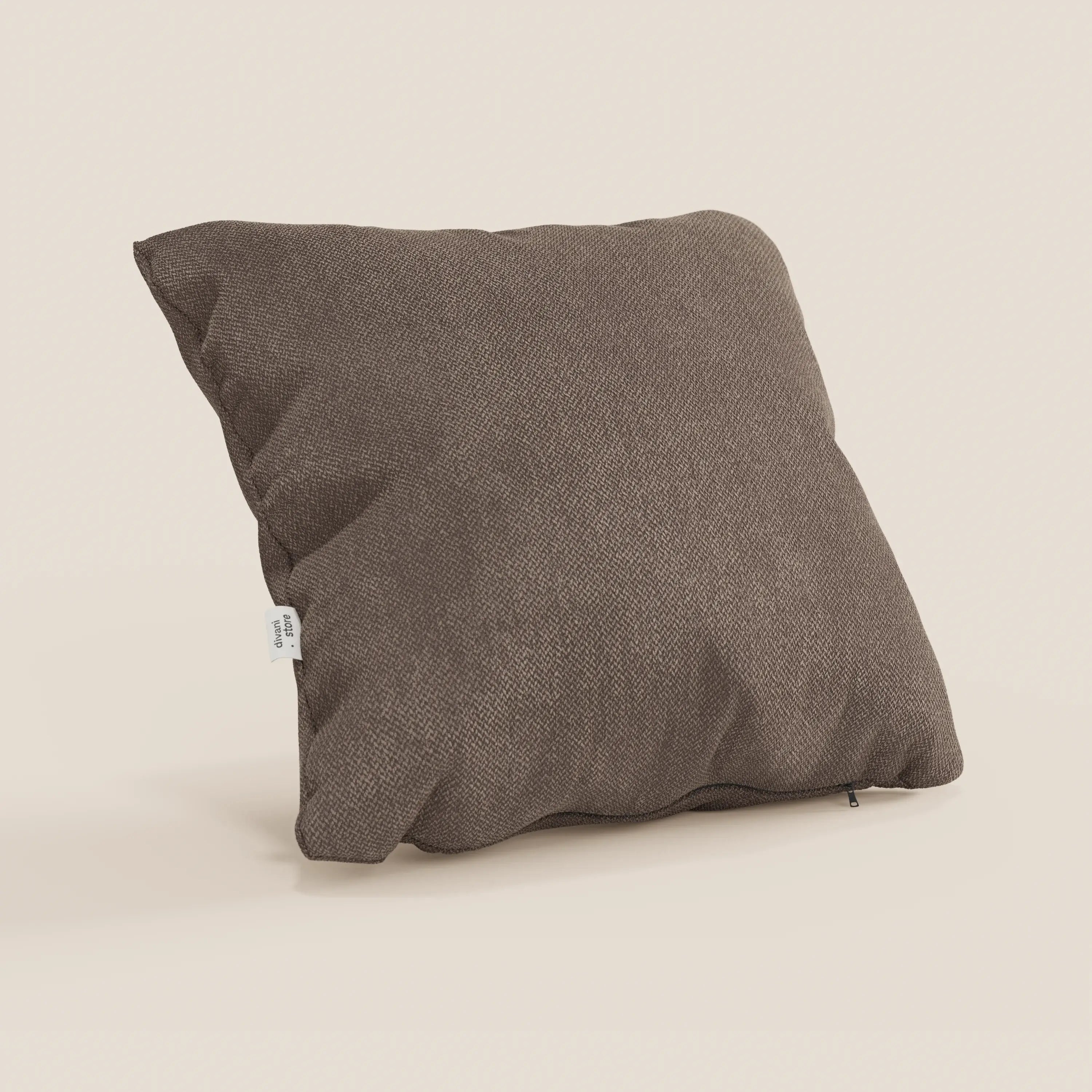 Il cuscino Sogno di Divani.Store, qui presentato nel colore SMACCHIABILE T05 marrone, è caratterizzato da un design quadrato con un tessuto marrone morbido e strutturato e un'etichetta con cucitura laterale. Il cuscino, esposto su uno sfondo beige chiaro, appare soffice e invitante.