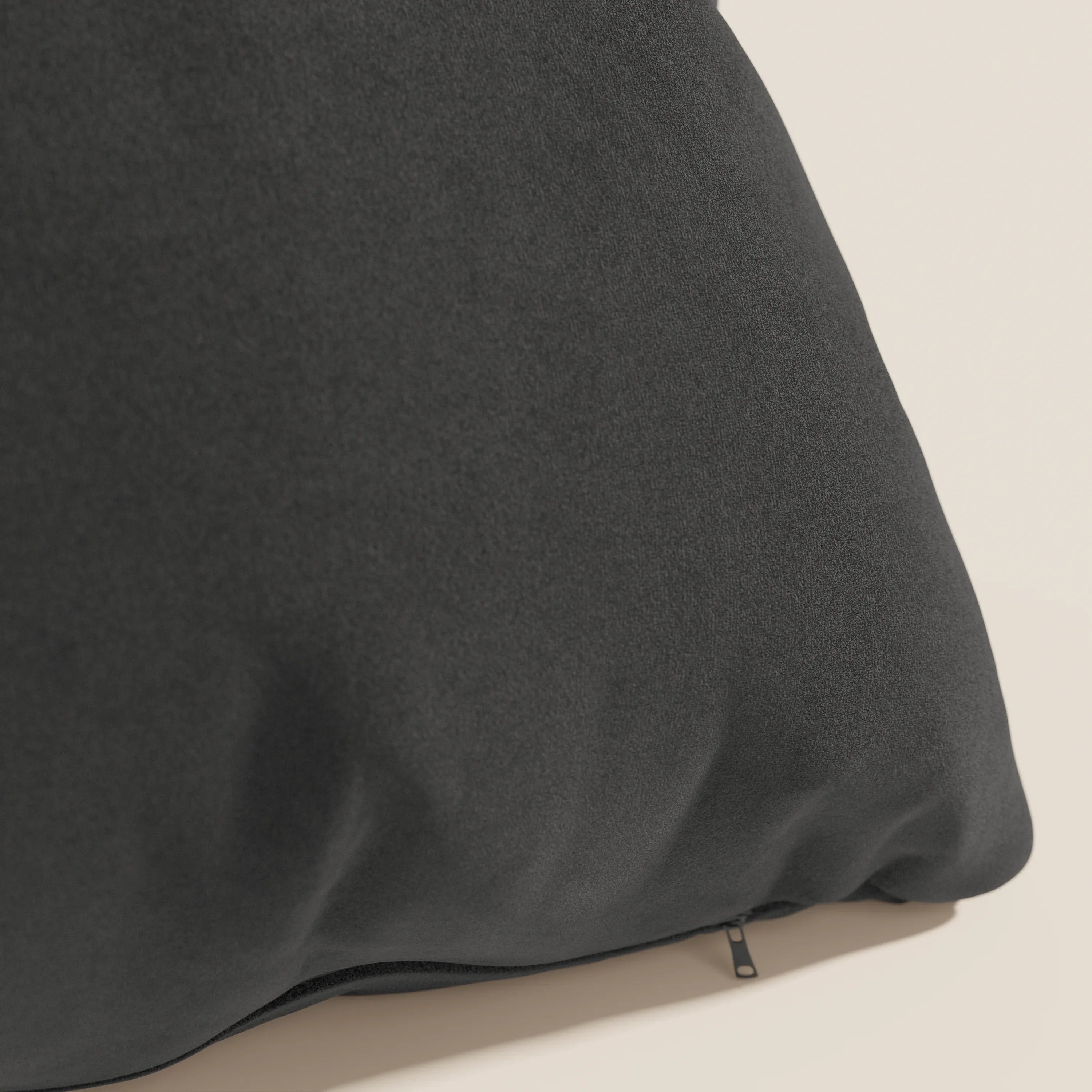 Primo piano del cuscino Jazz di Divani.Store in nero T11, realizzato in microfibra tecnica antimacchia. Il cuscino è caratterizzato da una texture sottile, è sfoderabile con cerniera nascosta ed è inserito in un semplice sfondo beige chiaro.