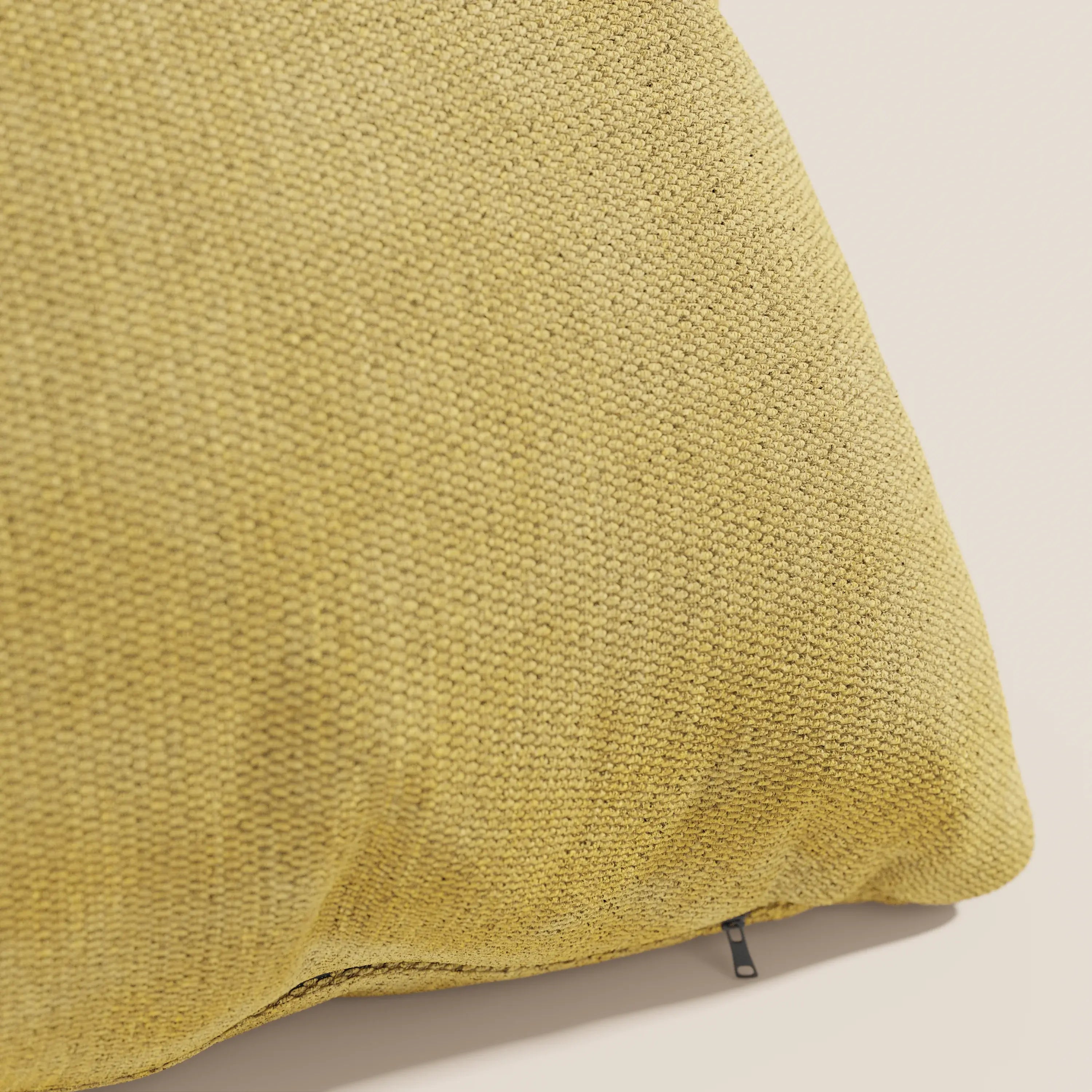 Primo piano del cuscino Miami 45x45 cm in T14 giallo di Divani.Store, realizzato in morbido tessuto impermeabile con motivo intrecciato e tirazip nero, su sfondo beige chiaro.