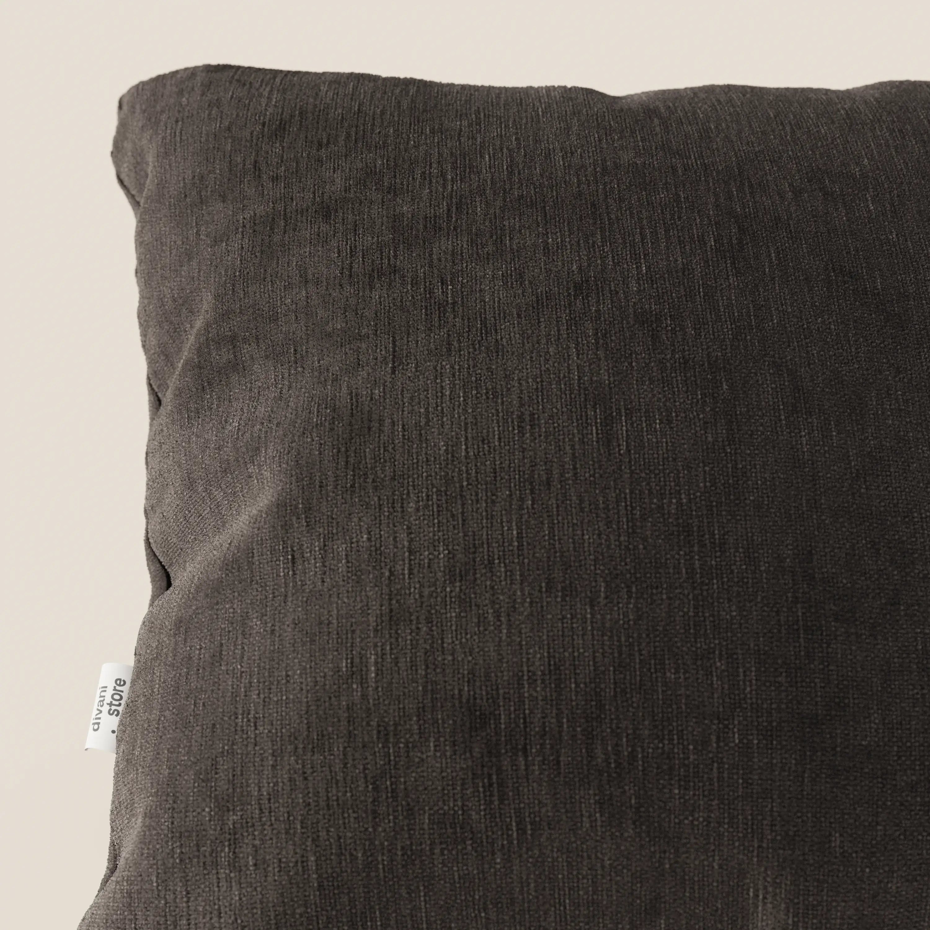 Primo piano del cuscino Bolero di Divani.Store in tessuto T31 grigio scuro, smacchiabile, impermeabile e irrestringibile. Il cuscino, dalla consistenza morbida, è mostrato in posizione obliqua su uno sfondo beige chiaro, con un'etichetta bianca visibile sul bordo sinistro.