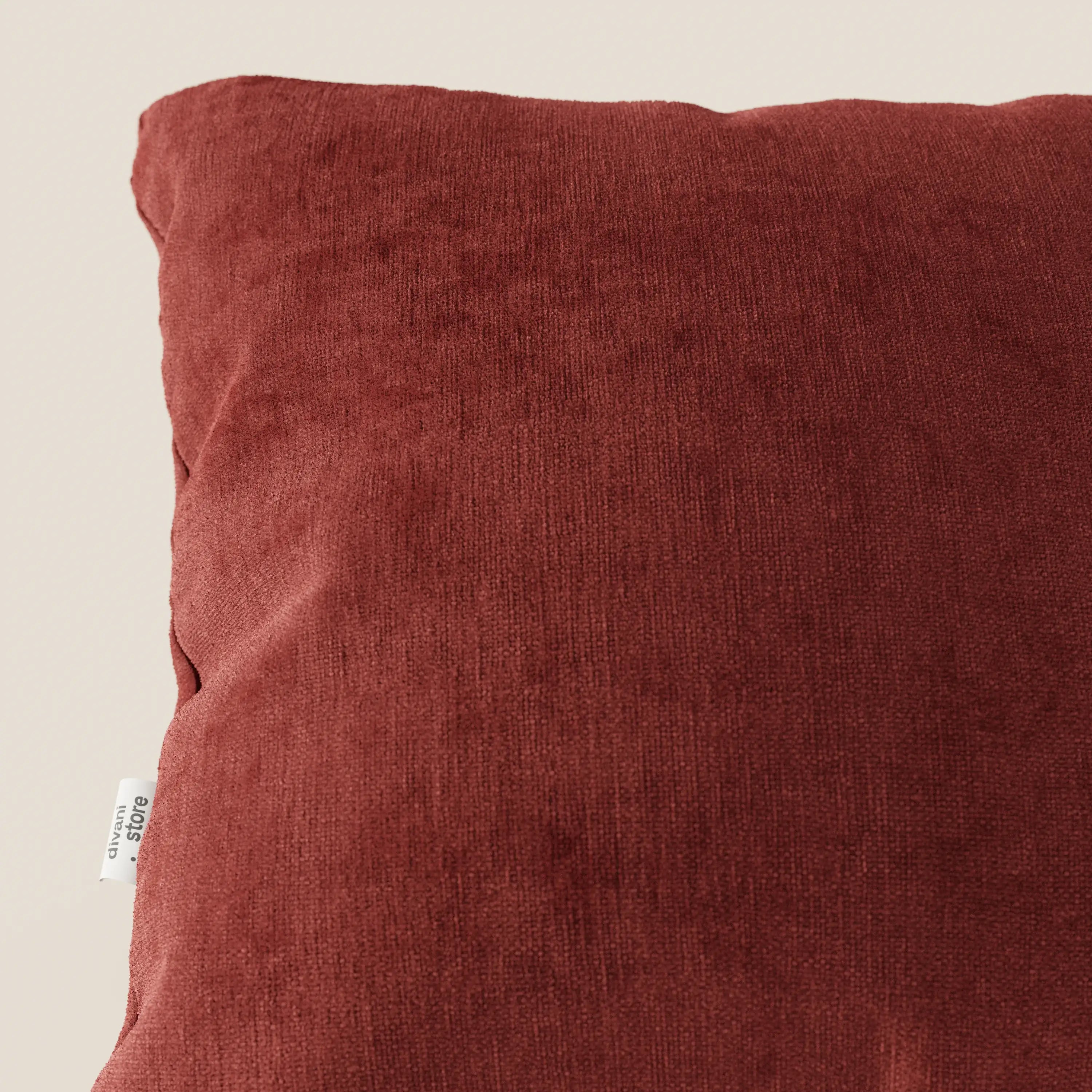 Primo piano del cuscino Bolero di Divani.Store in tessuto T31 marrone intenso, smacchiabile, impermeabile e irrestringibile, quadrato e strutturato con una piccola etichetta bianca, su sfondo beige chiaro. È visibile solo una parte del cuscino.