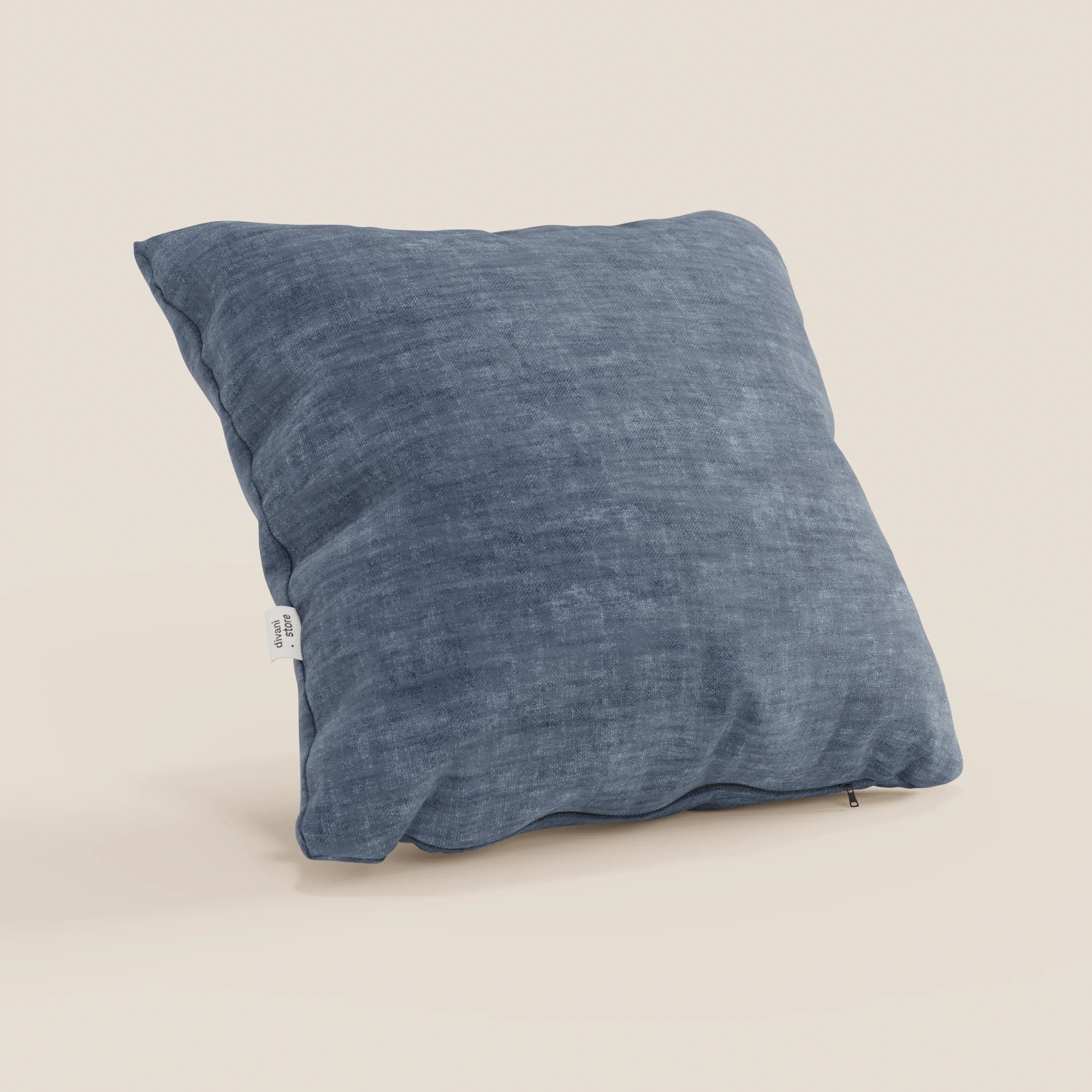 Il cuscino Sofia di Divani.Store, qui in blu, è caratterizzato da un morbido velluto nuvolato antimacchia e impermeabile (Easy Clean T35). È posizionato in verticale su uno sfondo beige con una piccola etichetta bianca sulla cucitura laterale.