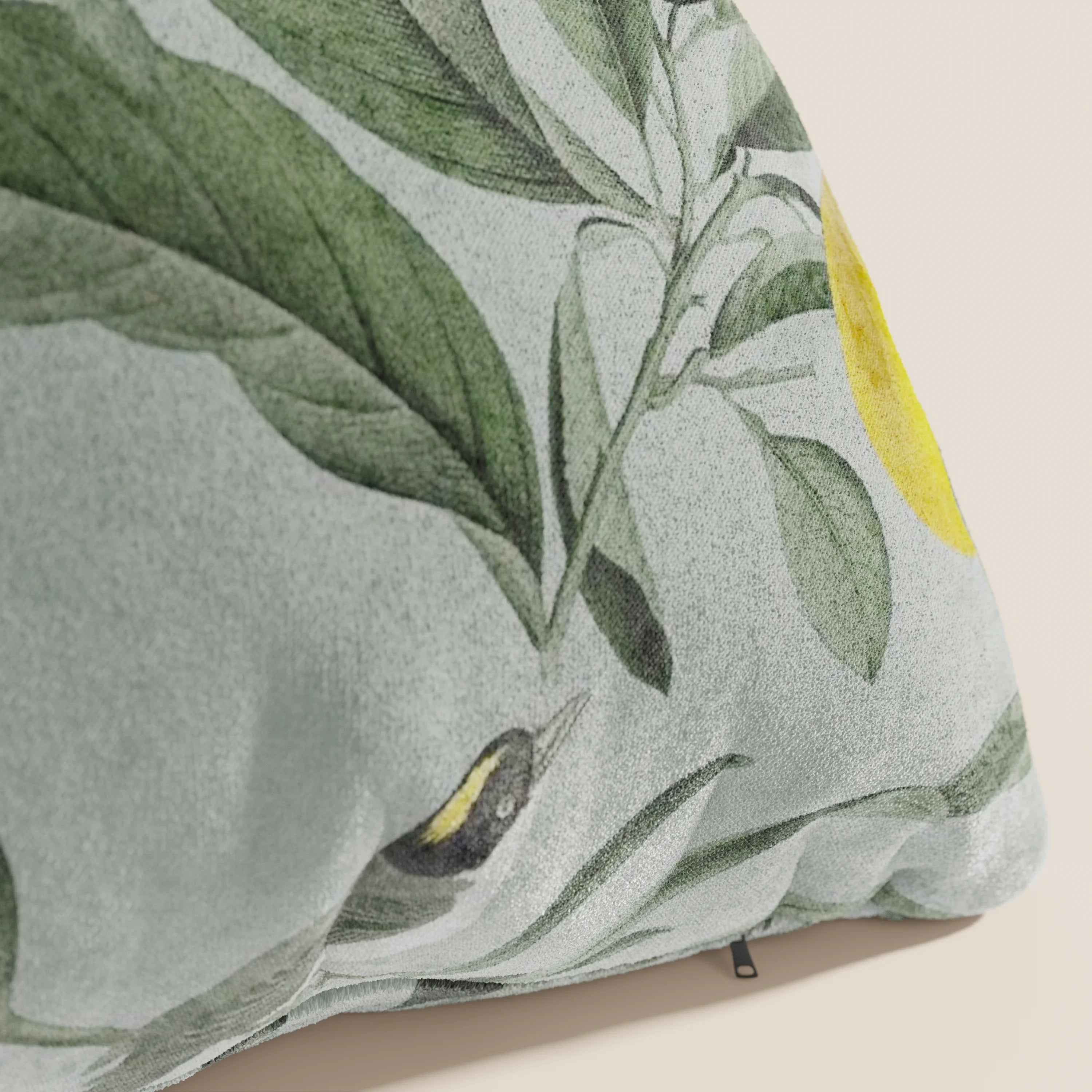 Un primo piano della collezione Lemon elegante di cuscini a fantasia in velluto impermeabile verde di Divani.Store mostra il suo design morbido e botanico con foglie verdi, un uccellino giallo e frutta per un tocco vintage.