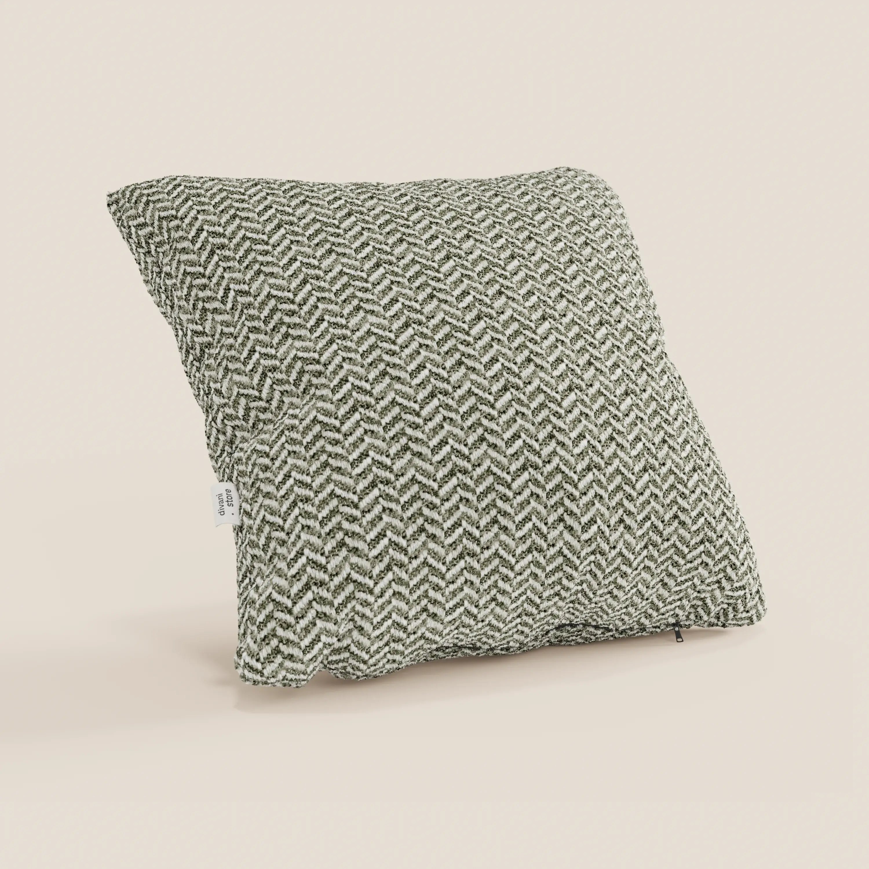 Il cuscino Sorrento 45x45 in lino | Eleganza Naturale di Divani.Store presenta un motivo a spina di pesce in rilievo nei toni del verde scuro e del bianco sporco, ripreso di sbieco con l'etichetta del tessuto su uno sfondo beige chiaro a tinta unita.
