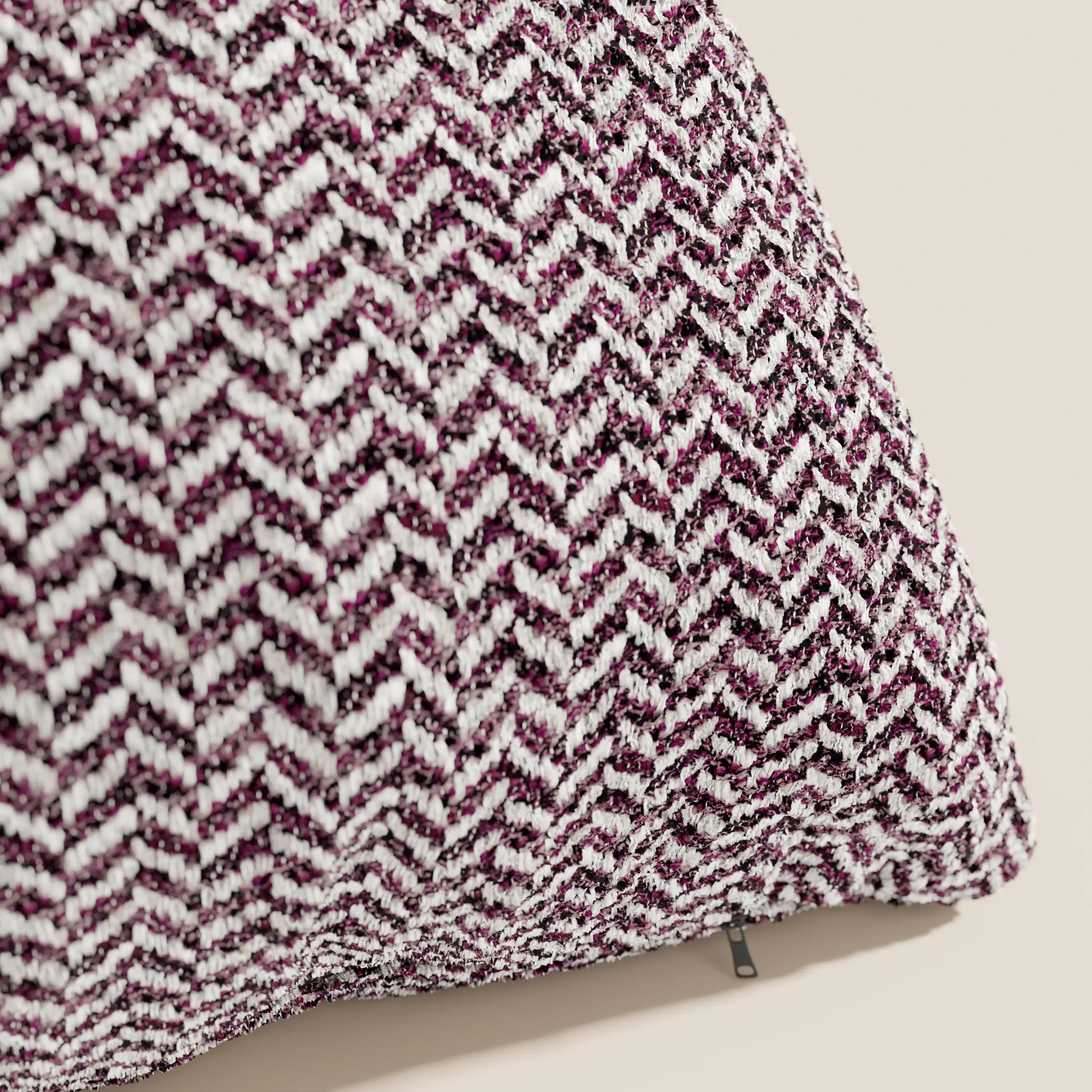 Primo piano del cuscino Sorrento 45x45 in lino di Divani.Store, caratterizzato da un motivo a zig-zag nei toni del bordeaux, nero e bianco con tirazip, su uno sfondo beige a tinta unita, per un look elegante e naturale.
