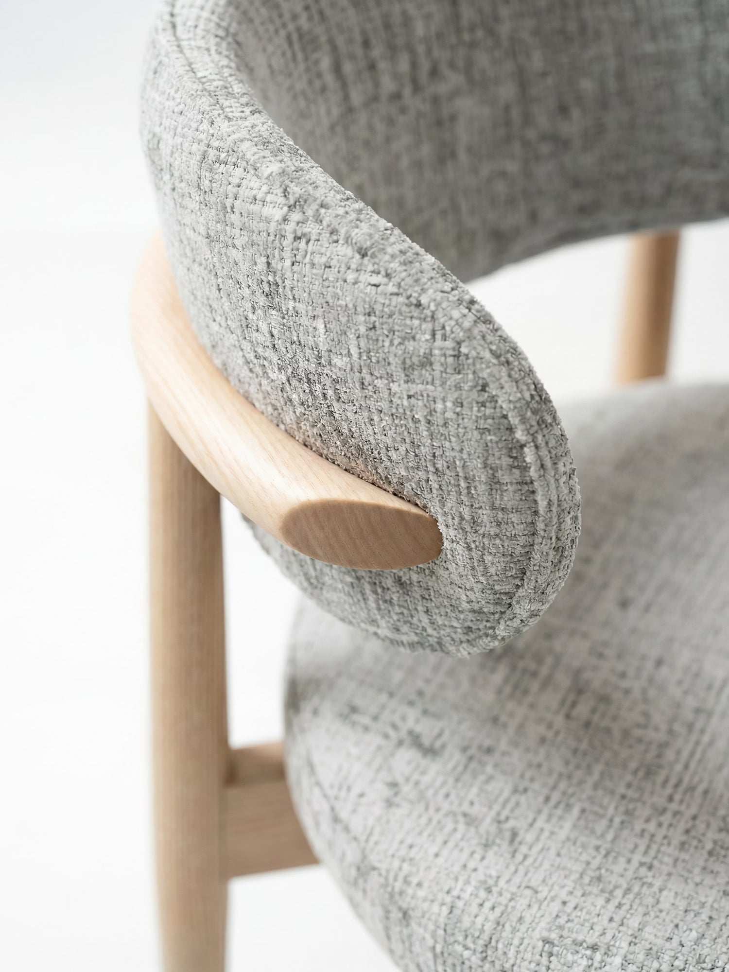 Primo piano della sedia imbottita Dafne di Divani.Store, caratterizzata da uno schienale curvo e imbottito in ciniglia certificata OEKO-TEX® e da inserti in rovere massello liscio e naturale che collegano lo schienale alla seduta.