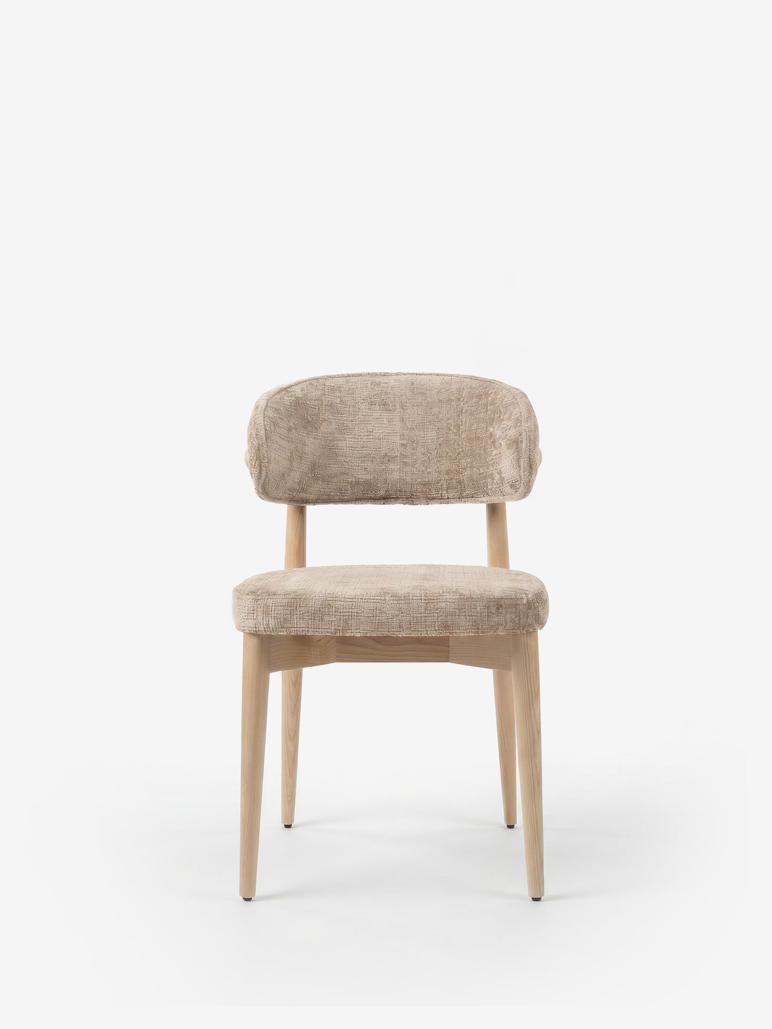 La sedia imbottita Dafne di Divani.Store presenta uno schienale arrotondato, una seduta imbottita in ciniglia certificata OEKO-TEX® e quattro gambe in rovere naturale massiccio. Il suo design minimalista e moderno risalta su uno sfondo bianco a tinta unita.