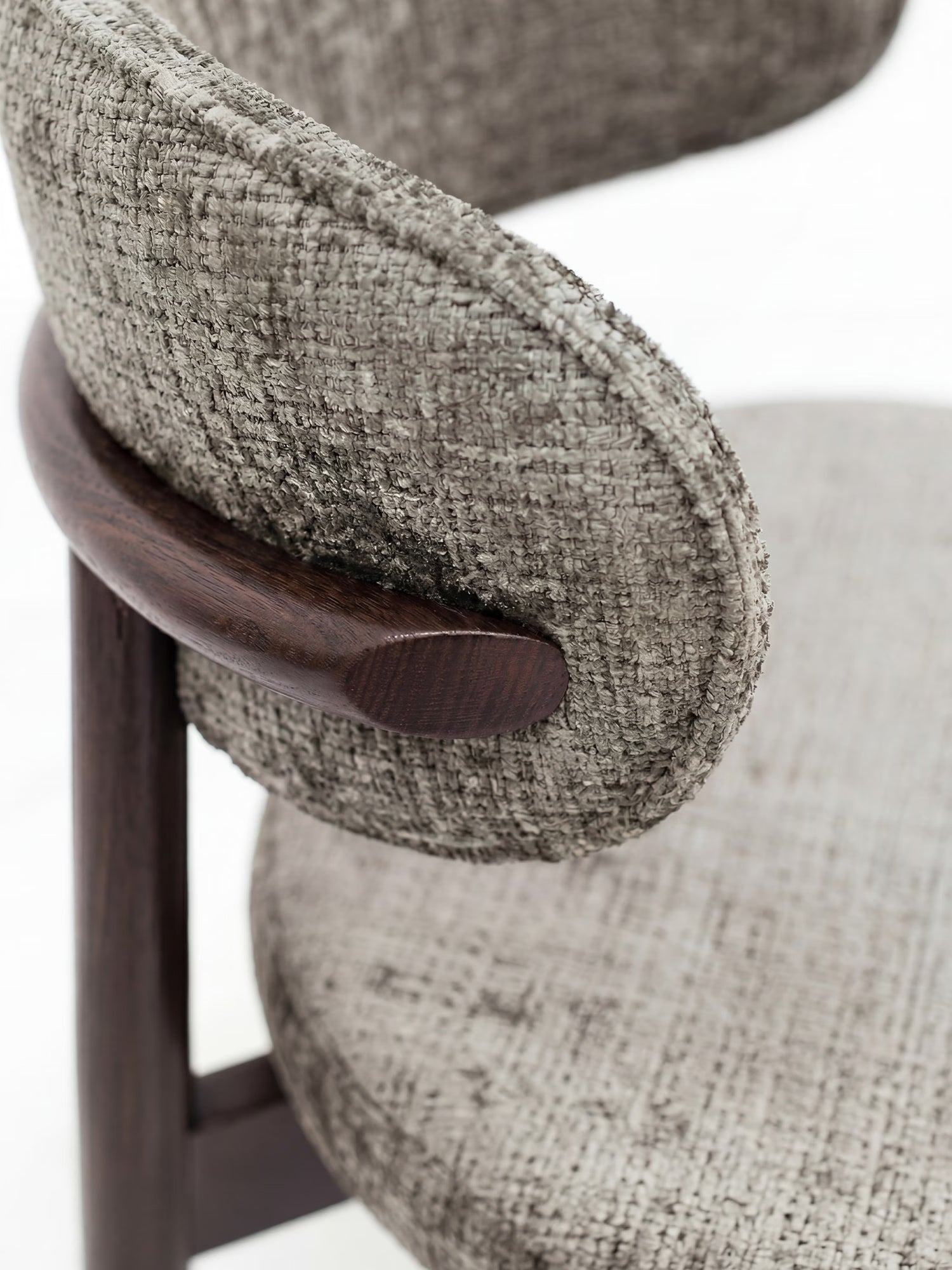 Primo piano della sedia imbottita Dafne di Divani.Store, realizzata in tessuto chenille grigio chiaro certificato OEKO-TEX® e caratterizzata da uno schienale arrotondato, con una struttura in legno massello wengé scuro che crea un suggestivo contrasto contemporaneo.