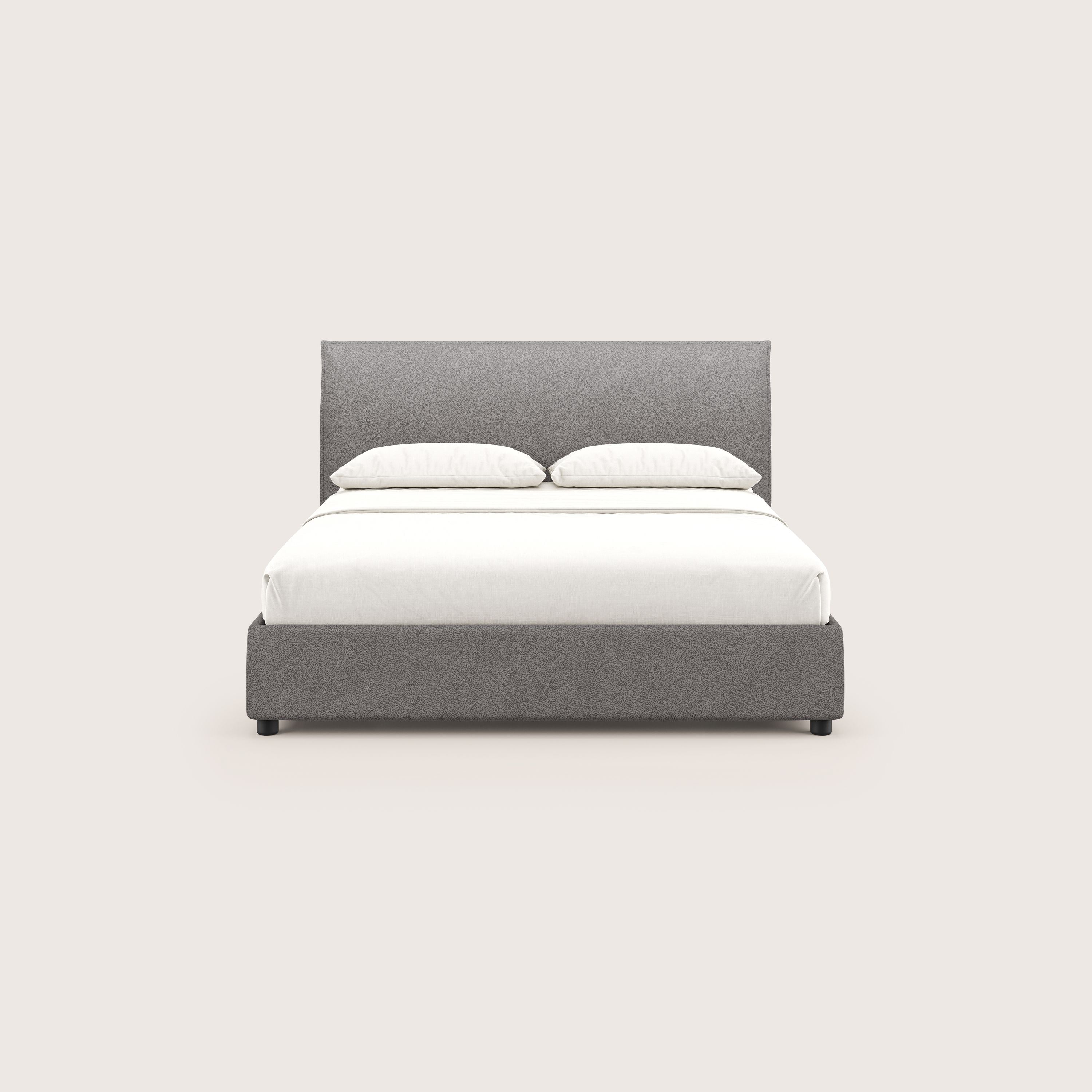 Il letto contenitore Nina di Letti.store è caratterizzato da un design minimal in microfibra antracite antimacchia effetto pelle, ordinatamente realizzato con lenzuola e due cuscini bianchi, centrati su uno sfondo beige chiaro.