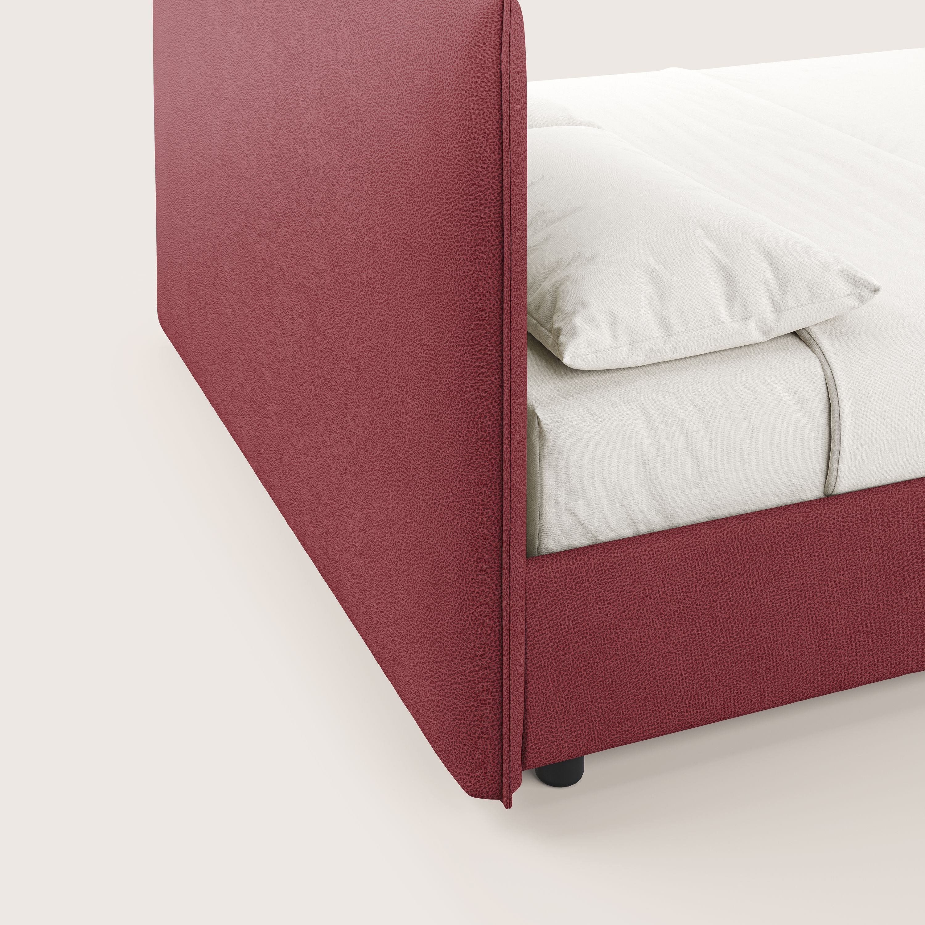 Primo piano di Nina letto contenitore di Letti.store, caratterizzato da una struttura in microfibra rossa antimacchia effetto pelle e da un letto bianco. L'immagine mette in risalto il design minimal italiano e le linee morbide su uno sfondo chiaro.