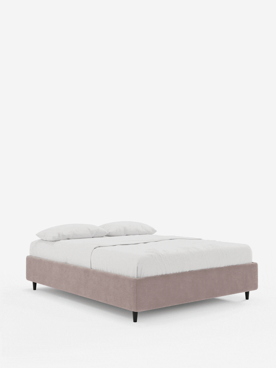 Letto ERON con rete imbottita e vano contenitore, rivestito in tessuto impermeabile certificato Oeko-Tex color rosa polveroso, con struttura imbottita in stile minimalista, gambe affusolate scure e biancheria da letto candida su uno sfondo grigio chiaro.