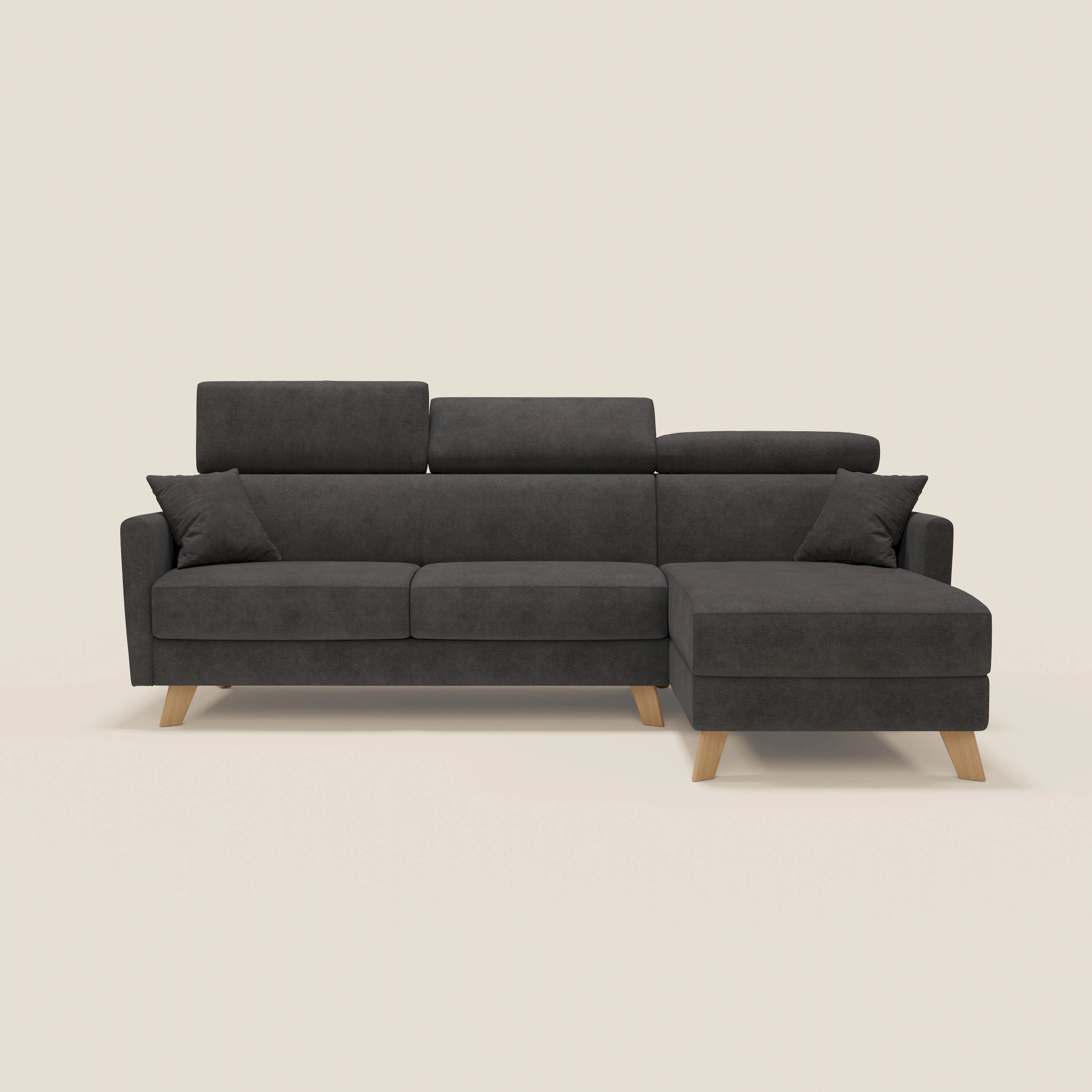 Divano moderno Francy letto angolare sfoderabile di Divani.Store in T17 antracite, con penisola contenitore, poggiatesta reclinabili, gambe in legno, due cuscini di seduta e cuscini su fondo beige chiaro.