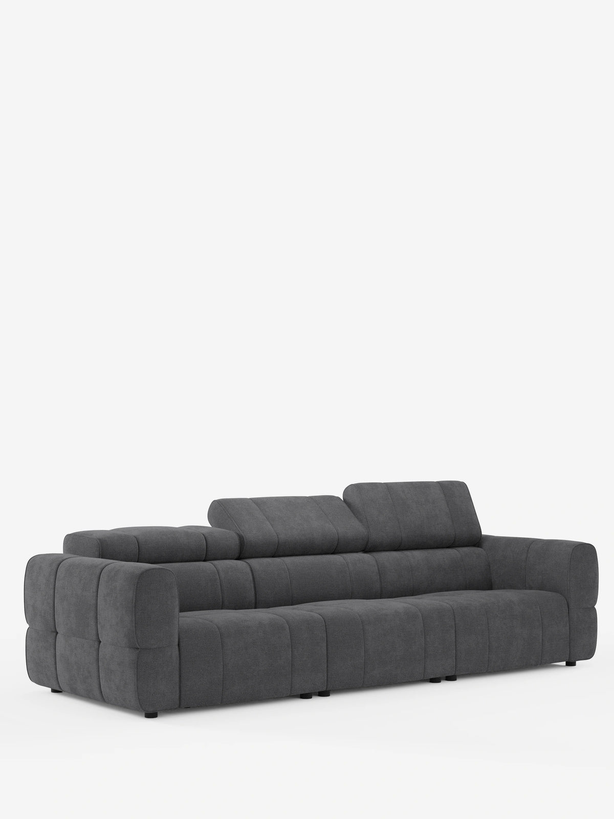 Su uno sfondo bianco spicca un divano modulare Giotto a 4 posti, di colore grigio scuro, dotato di poggiatesta reclinabili e funzione relax elettrica opzionale, realizzato in tessuto smacchiabile T23 con design trapuntato e a pannelli, ampi braccioli e poggiatesta regolabili.