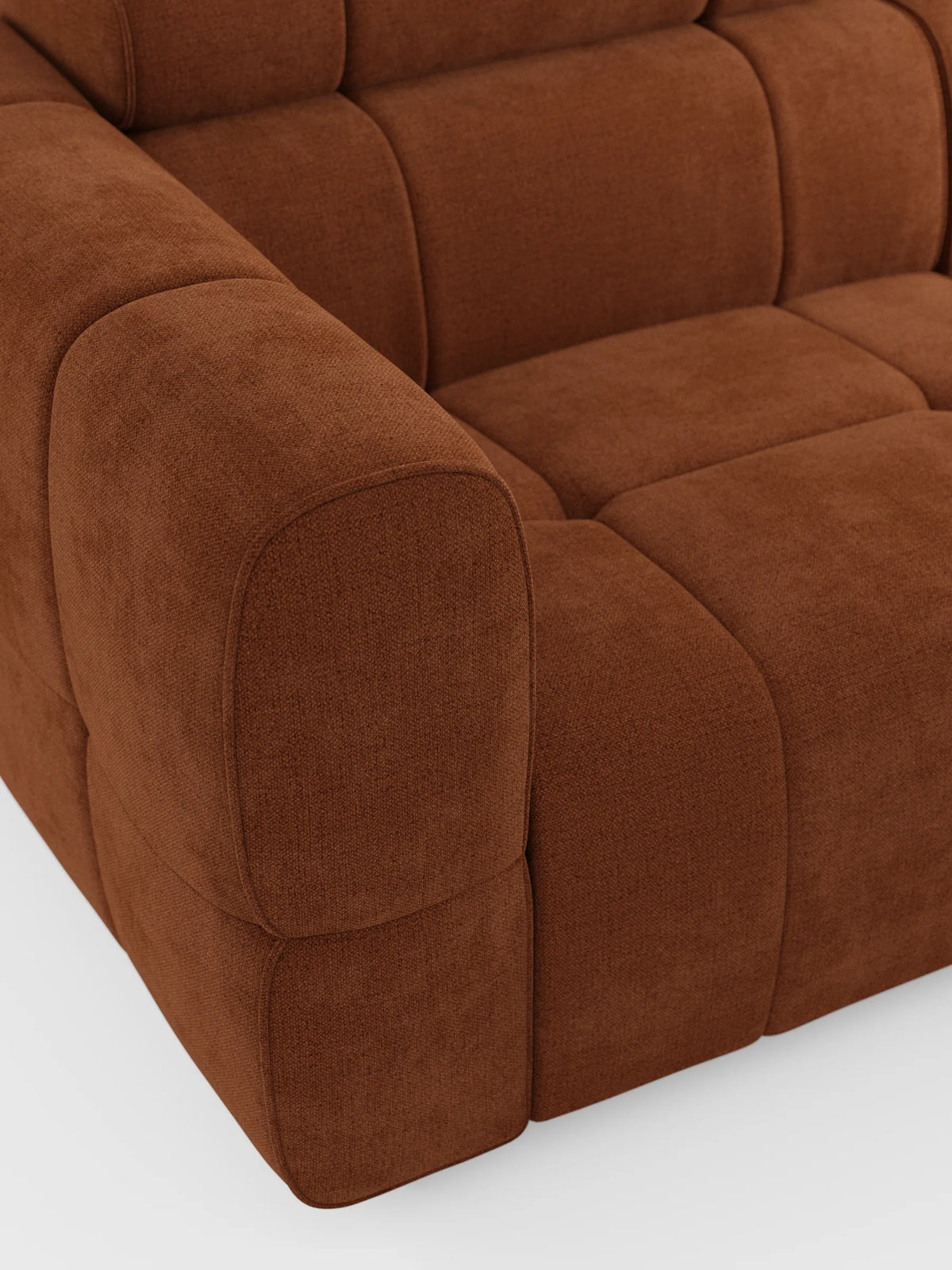 Un primo piano del divano angolare modulare Giotto a 5 posti da 296 cm con penisola e funzione relax elettrica opzionale, rivestito in tessuto smacchiabile T23, caratterizzato da cuscini color terracotta con effetto testurizzato, cuciture quadrate e braccioli arrotondati su uno sfondo chiaro.