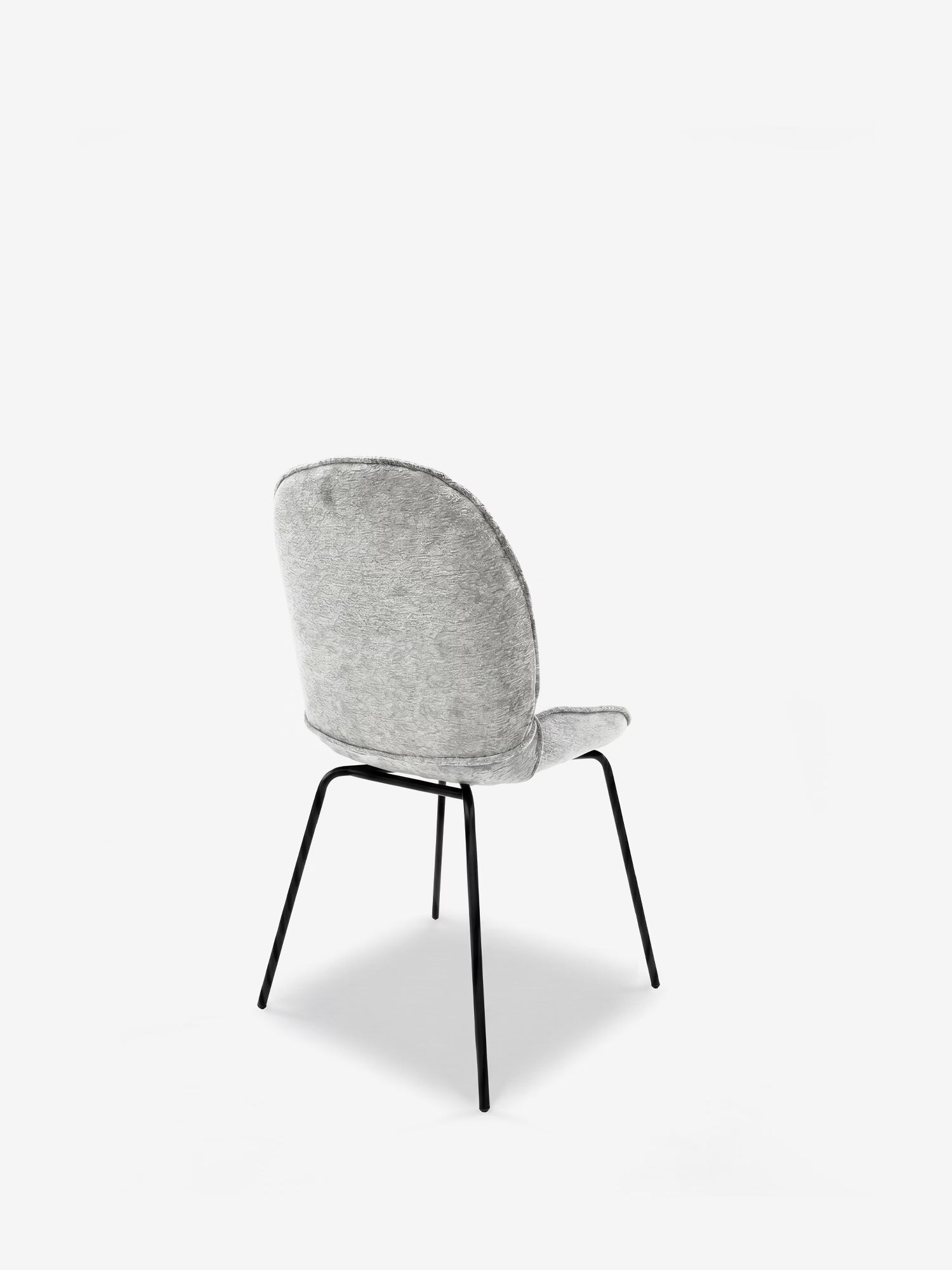 La sedia Iride, imbottita in morbido tessuto materico di Divani.Store, con struttura in metallo nero e design minimalista, è raffigurata di spalle su uno sfondo bianco per mettere in risalto la morbidezza della seduta e lo stile moderno.