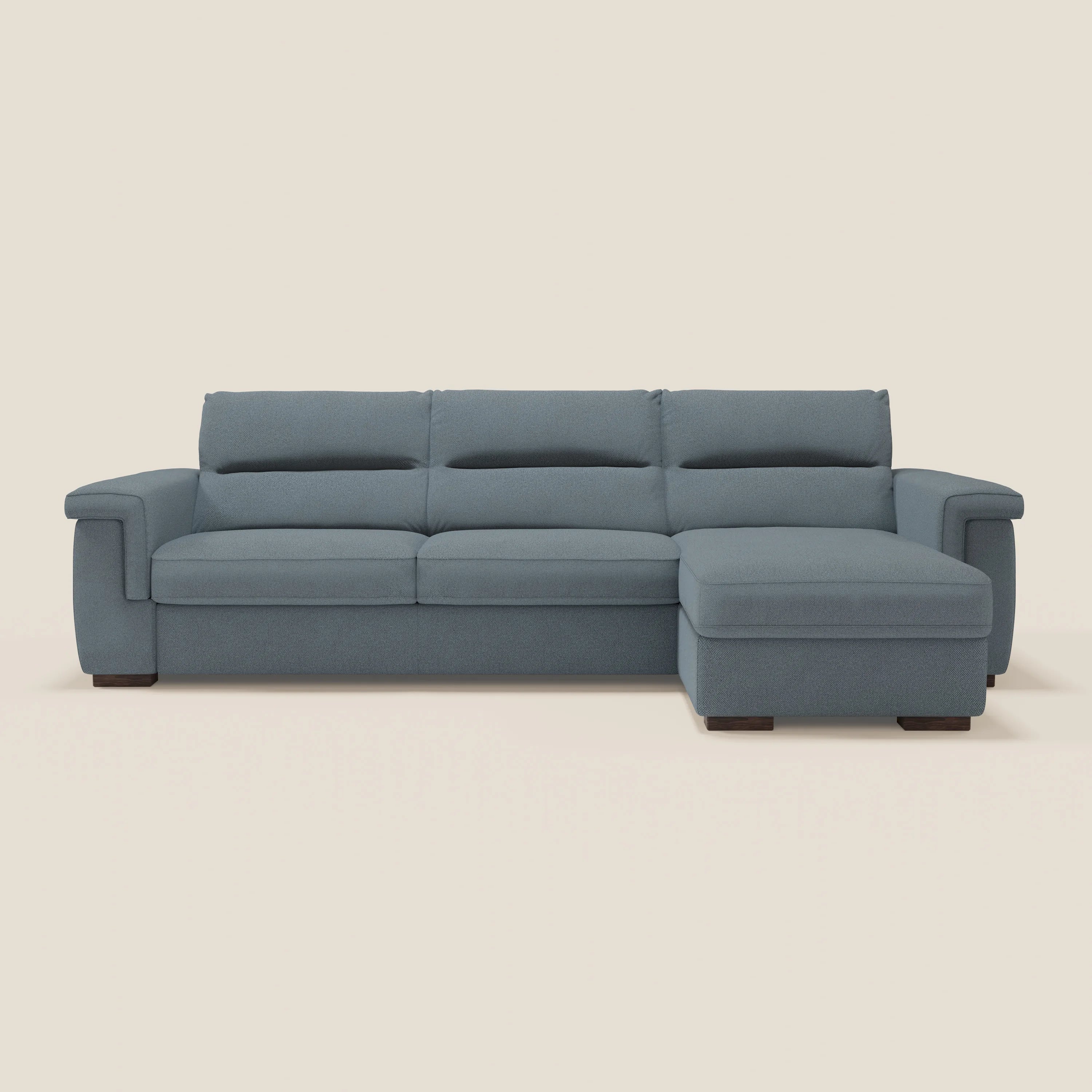 Il divano letto Magnolia angolare con penisola contenitore di Divani.Store in tessuto smacchiabile T05 carta da zucchero, materasso H18 cm, offre Comfort Profondo con ampi braccioli e chaise longue destra su sfondo chiaro.