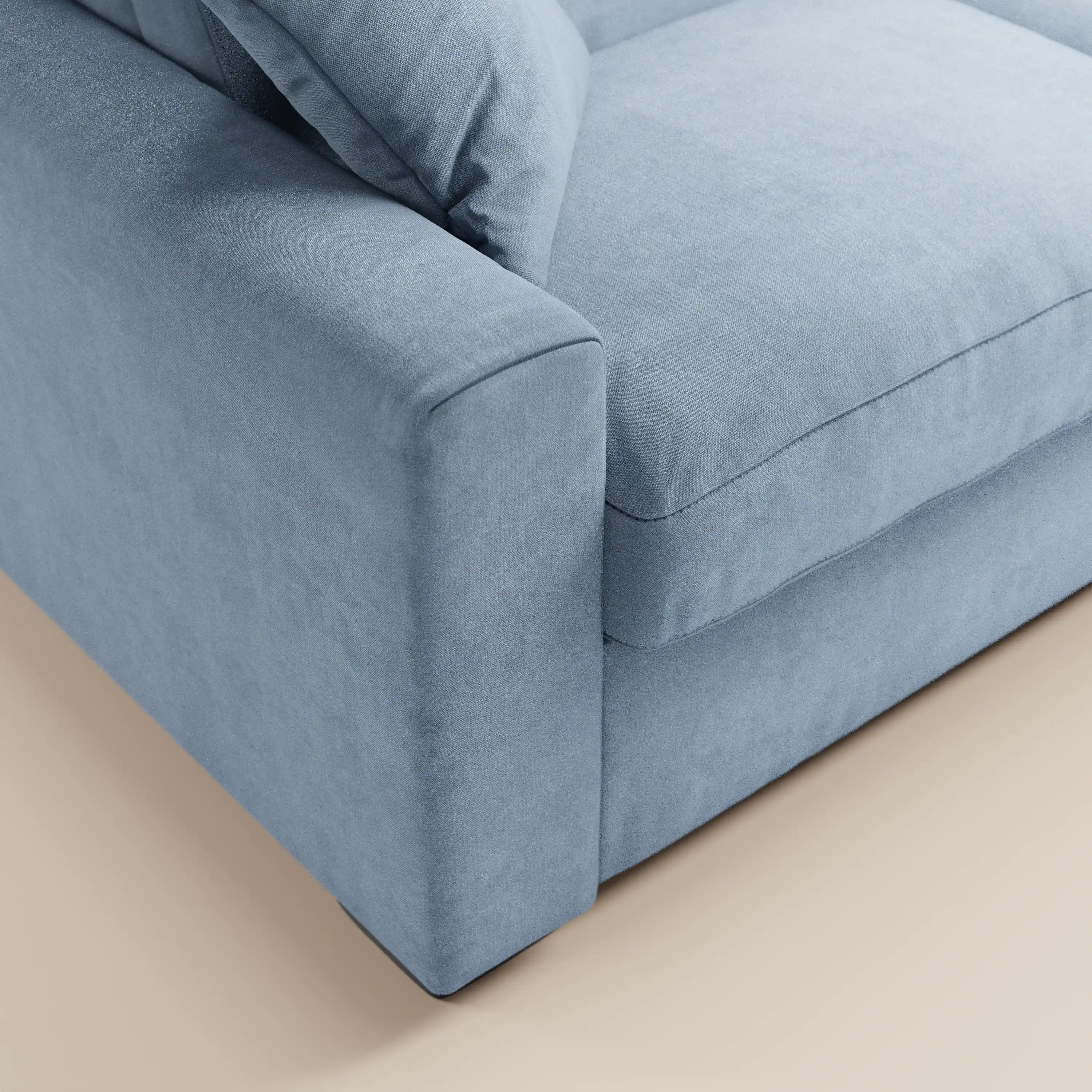 Primo piano del divano letto a 3 posti Maximus di Divani.Store, caratterizzato da una seduta imbottita, braccioli spessi e morbidi cuscini dello schienale in tessuto Oeko-Tex antimacchia, su uno sfondo beige chiaro. Include un materasso alto 20 cm e poggiatesta reclinabili.